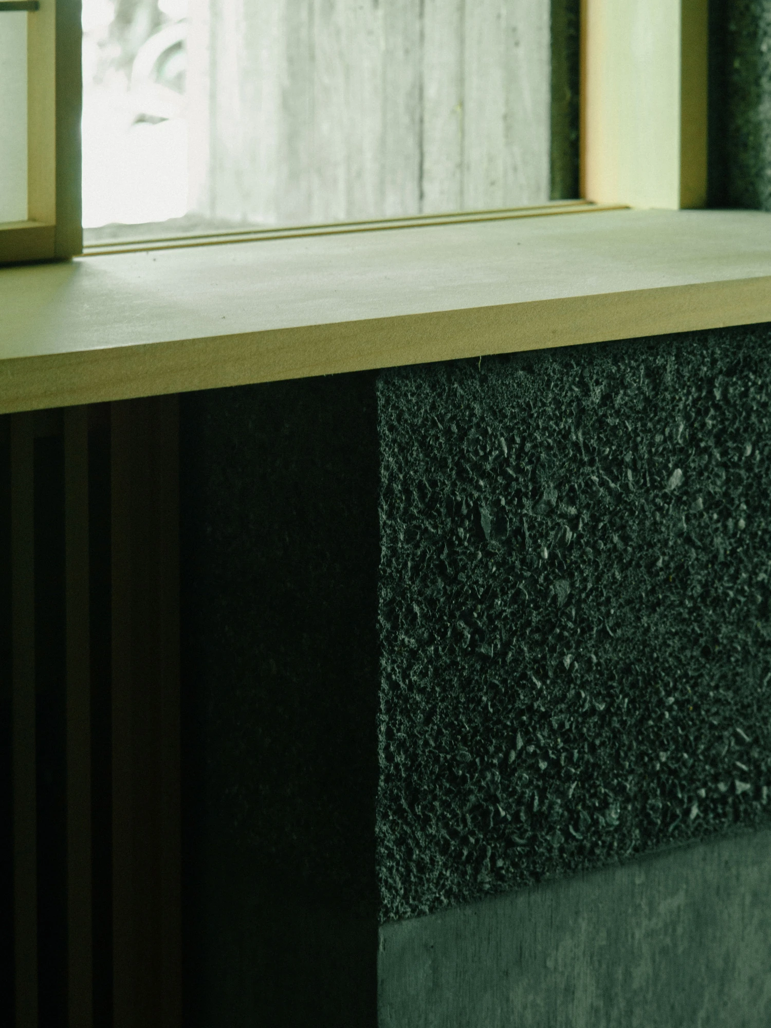 Konkuri-an by Teitakusubako, Yusuke Igarashi Architects, photographed by Kentaro Nemoto, Kazumasa Harada — Detail of the high-pressure washed concrete, its exposed aggregate meeting the plywood-grained lower panel at a timber sill.