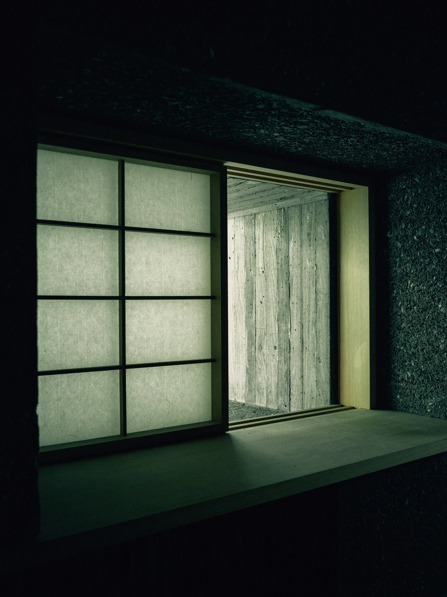 Konkuri-an by Teitakusubako, Yusuke Igarashi Architects, photographed by Kentaro Nemoto, Kazumasa Harada — A paper screen drawn aside on plywood-grained concrete, the timber formwork's grain held in the cured wall.