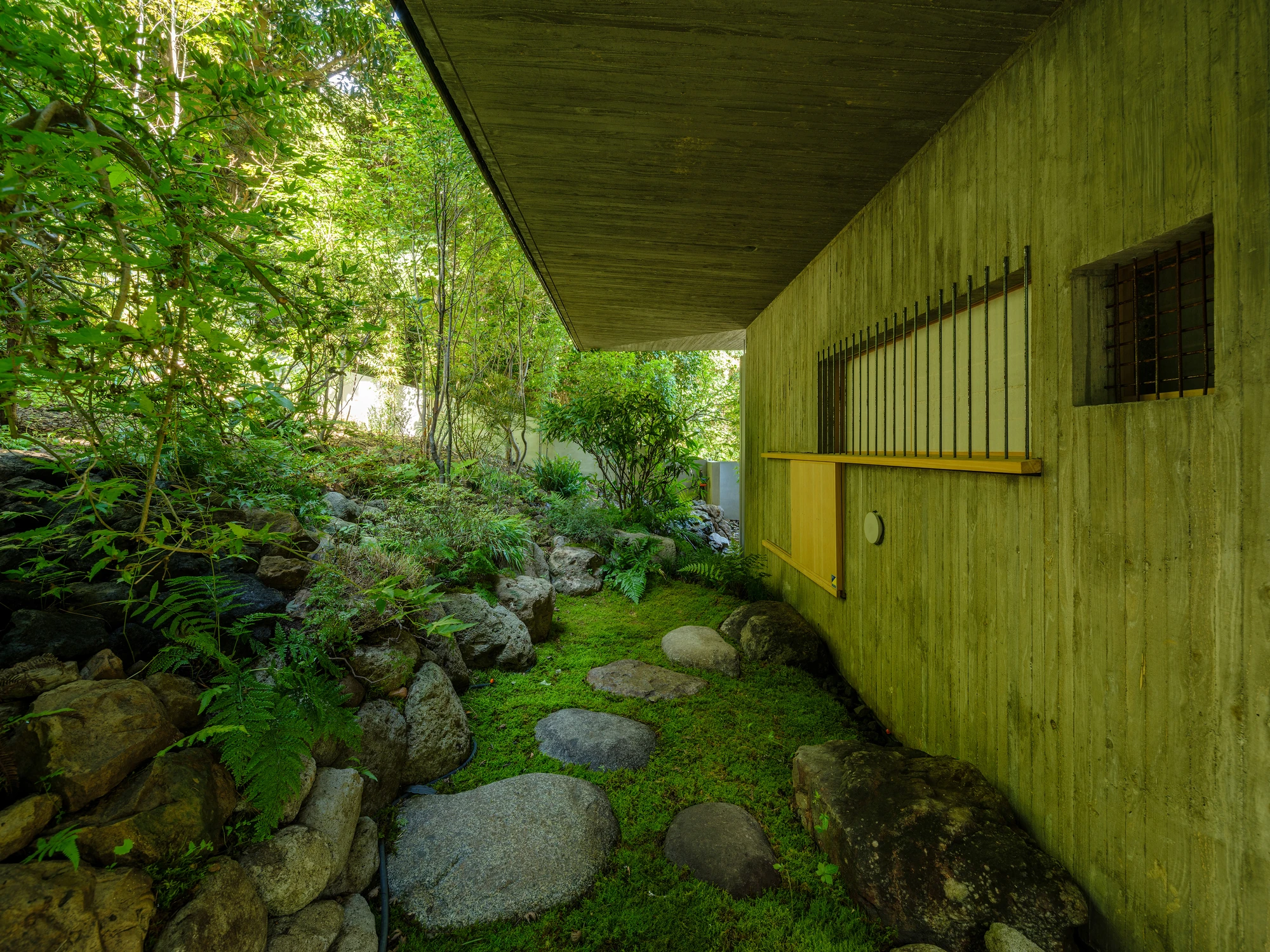 Konkuri-an by Teitakusubako, Yusuke Igarashi Architects, photographed by Kentaro Nemoto, Kazumasa Harada — The shitaji-mado seen from outside, reinforcing bars replacing the bamboo lattice in the concrete wall above the valley planting.