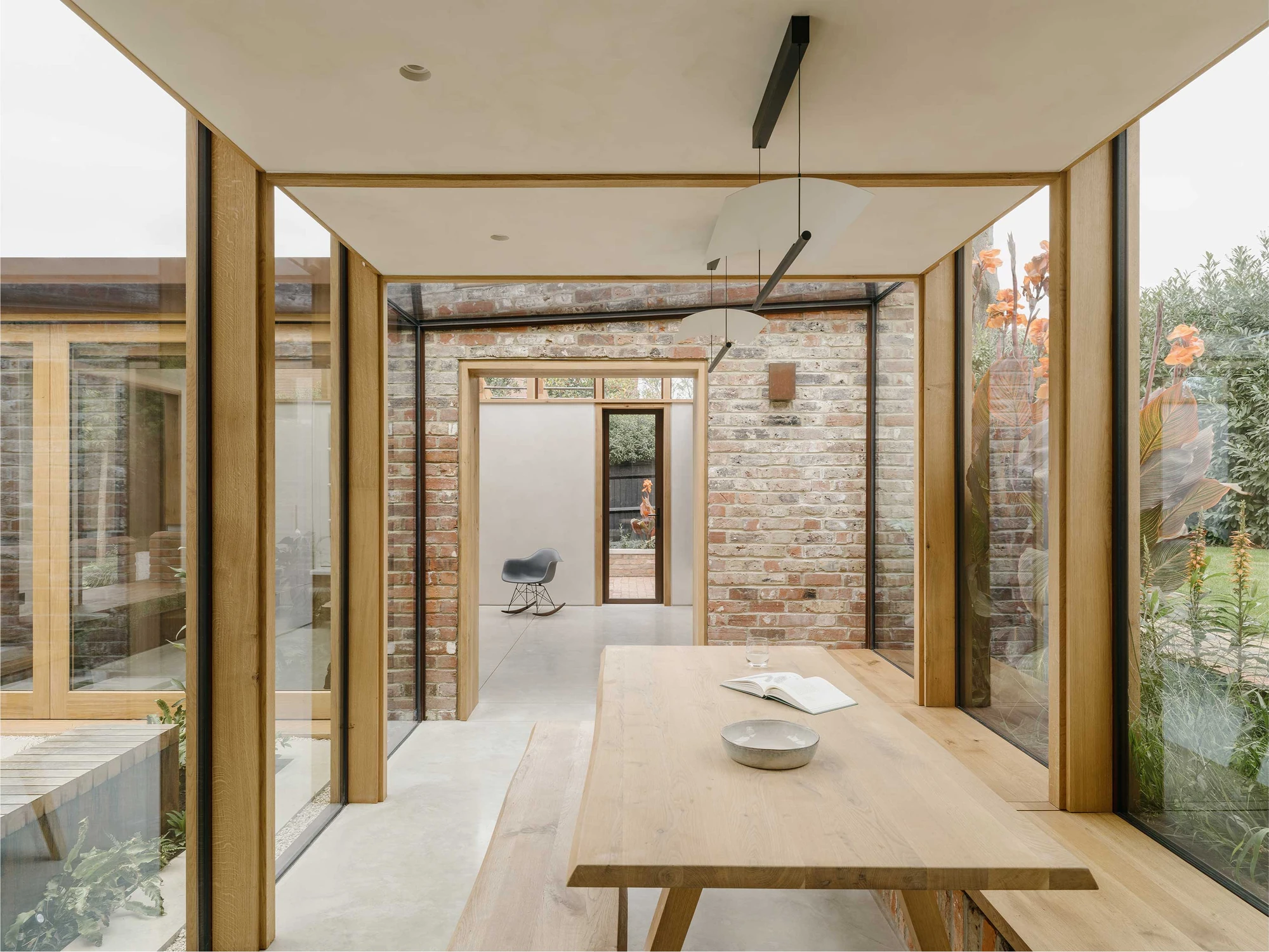 Muttram Veedu by Will Gamble Architects, photographed by James Retief — Full-height glazing wraps the dining corner, timber mullions holding the view onto the planted courtyard.