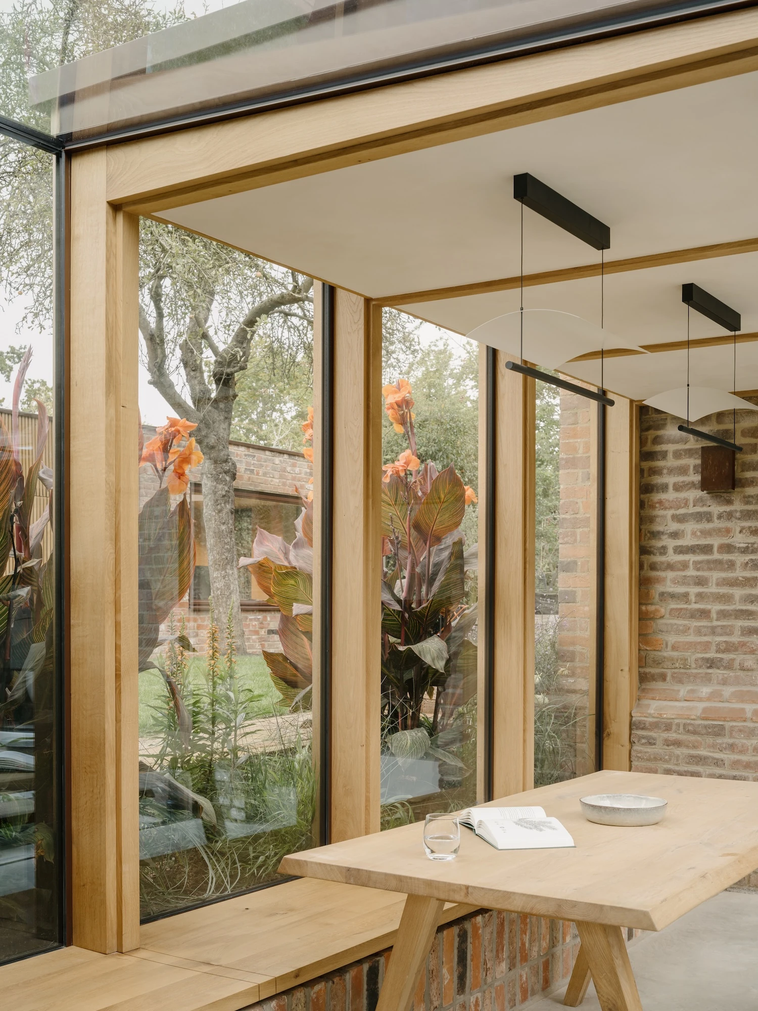 Muttram Veedu by Will Gamble Architects, photographed by James Retief — The oak-framed glazed dining bay opens toward the courtyard, its planting pressing against the glass.