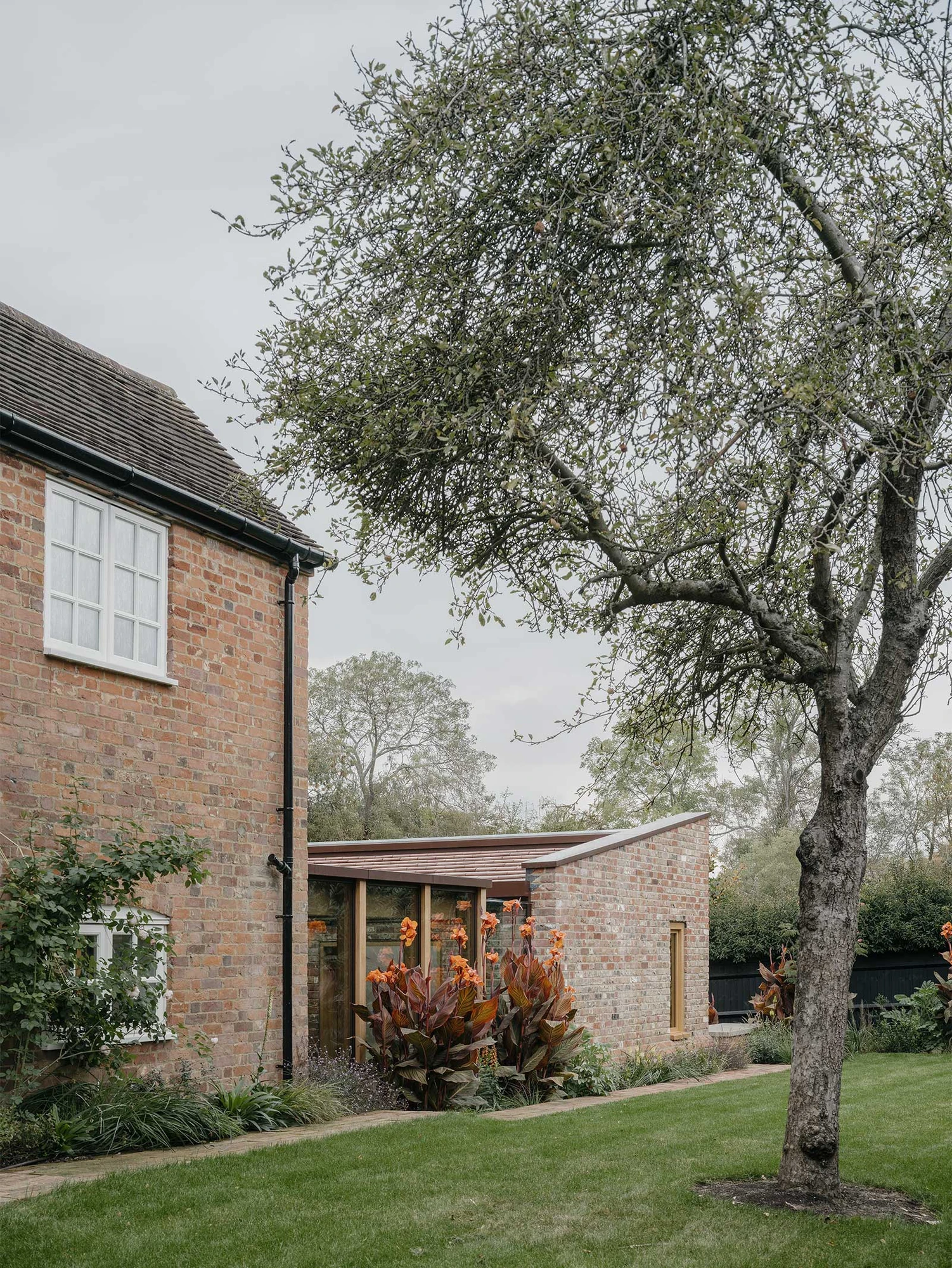 Muttram Veedu by Will Gamble Architects, photographed by James Retief — Open French doors reveal the sapele kitchen joinery and an old plank door deeper in the cottage.