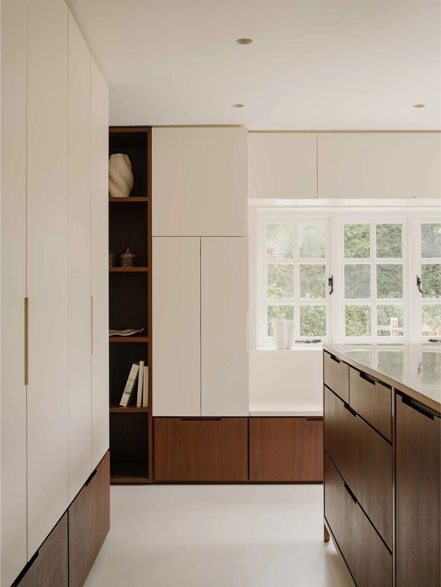 Muttram Veedu by Will Gamble Architects, photographed by James Retief — Sapele kitchen joinery with open shelving stands against pale cabinetry, the island top catching light from a cottage window.