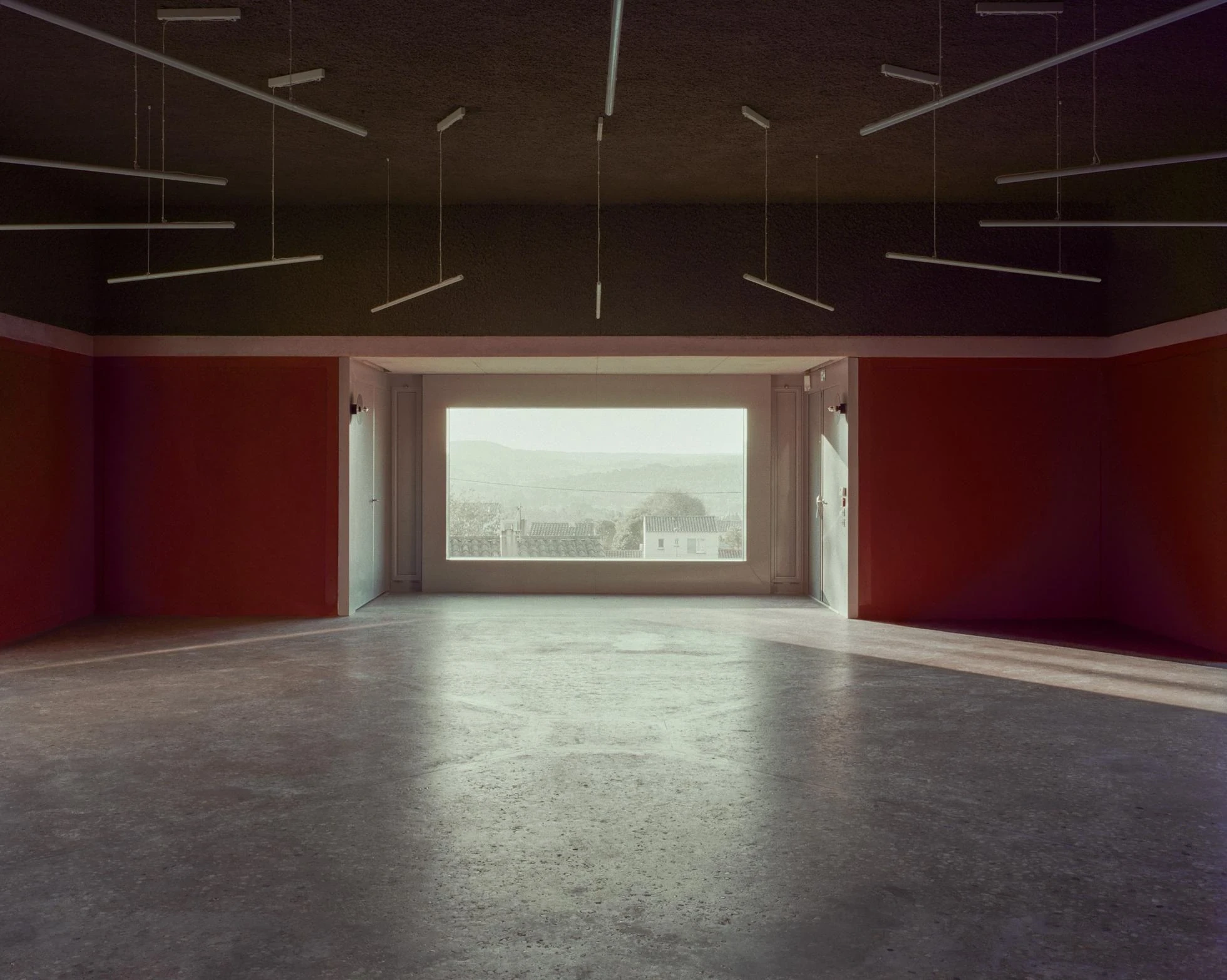Cultural and Community Center, Coudoux by atelier EGR, photographed by Giaime Meloni — A deep fixed frame set in a lowered alcove turns the upper room toward a distant view.