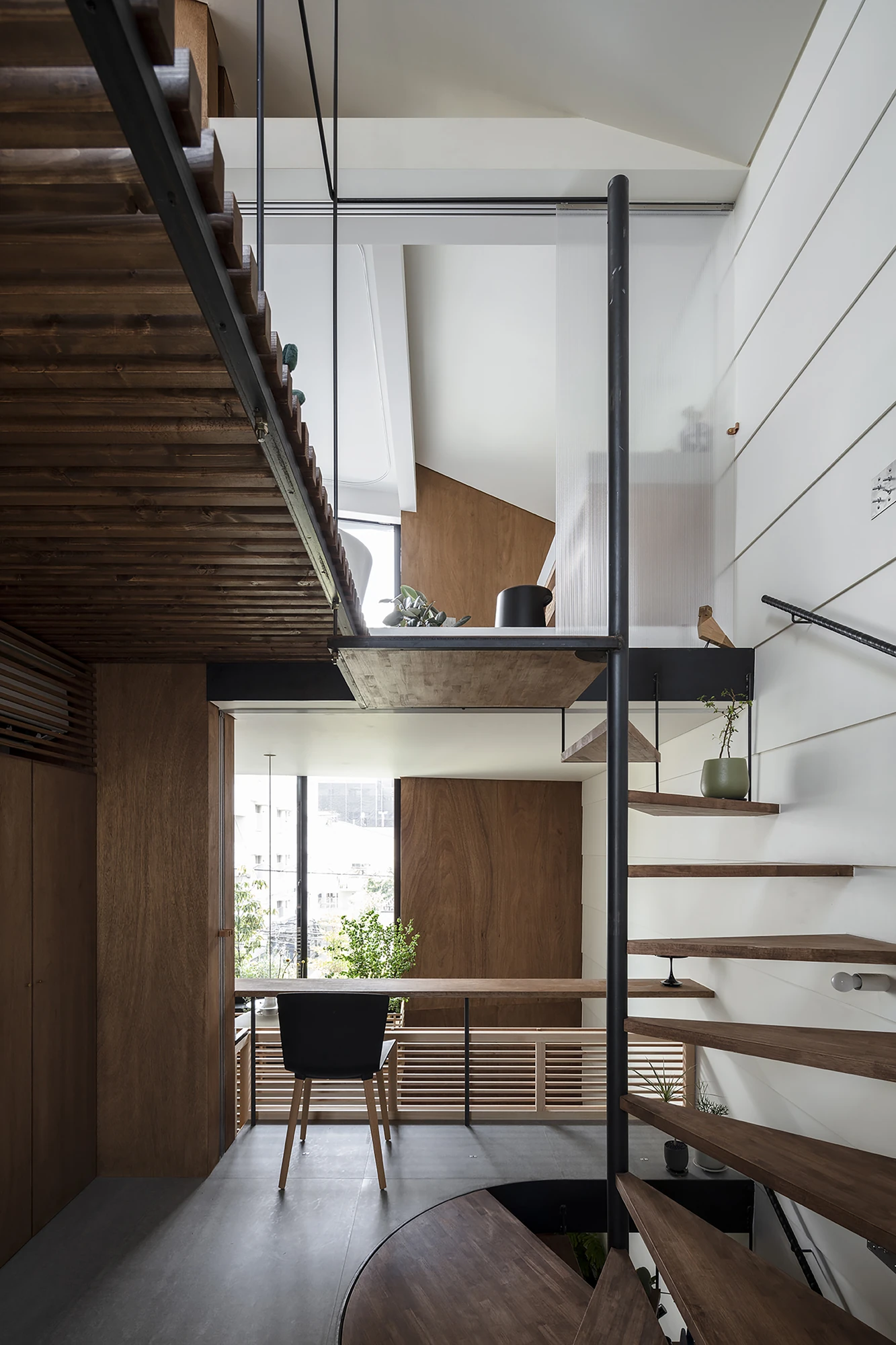 House in Kagurazaka by Takumi Wakui + Riho Wakui Architects — The multi-storey void threads the timber floors together, framed windows opening to the street between the stacked levels.