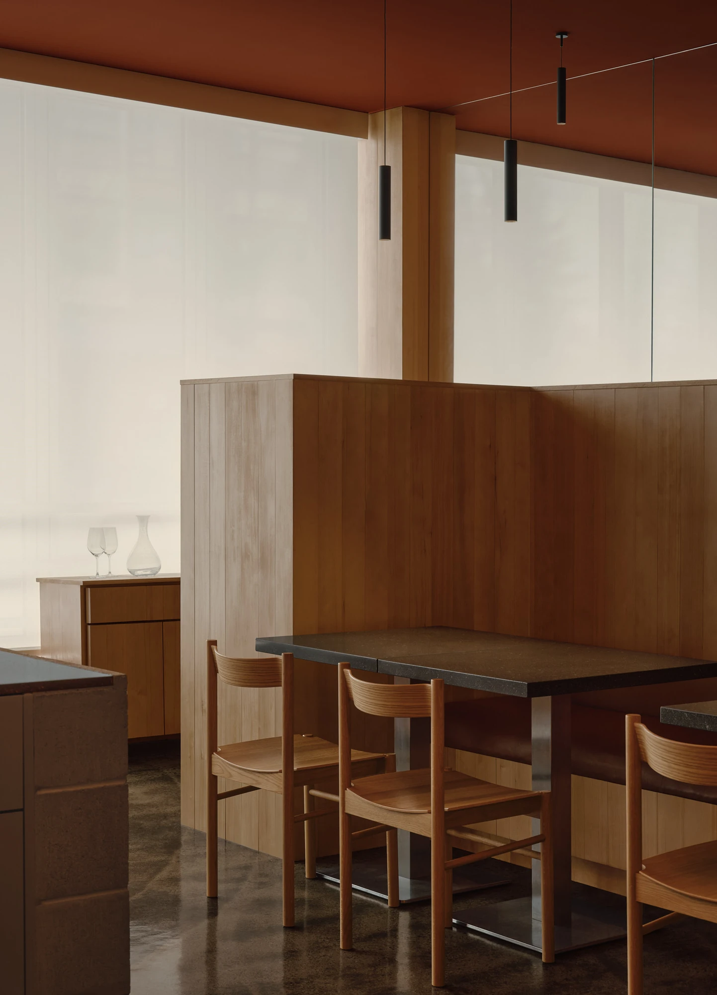 Jeju by &Daughters, photographed by Alex Lesage — A hand-thatched fixture suspended beside a frosted floor-to-ceiling window over a banquette and basalt-topped tables.