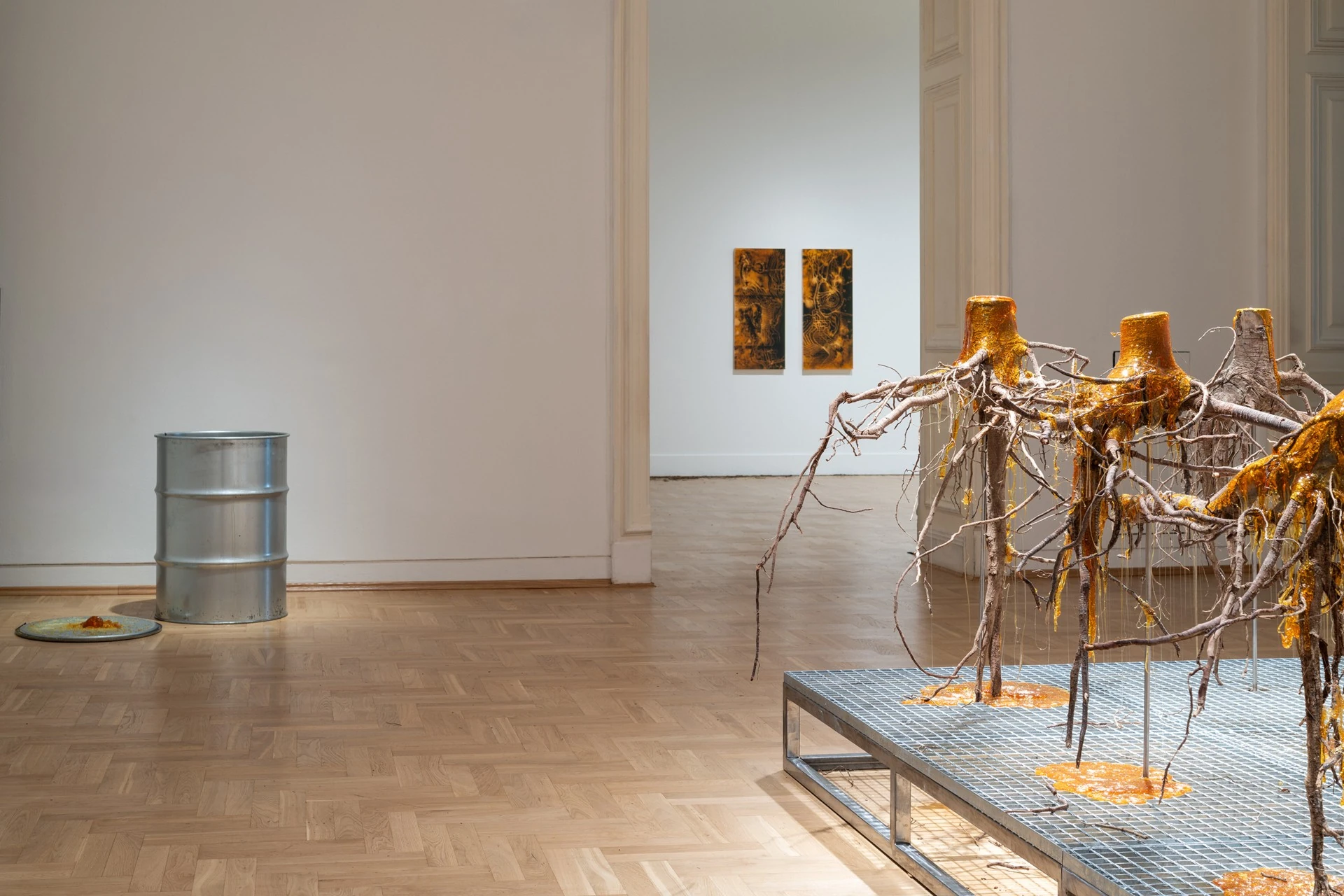 Żywica* Solar Plexus by Jura Shust, photographed by Maciej Landsberg — Żywica* Solar Plexus, spruce roots sealed in resin on a metal platform, a metal drum and amber panels beyond.
