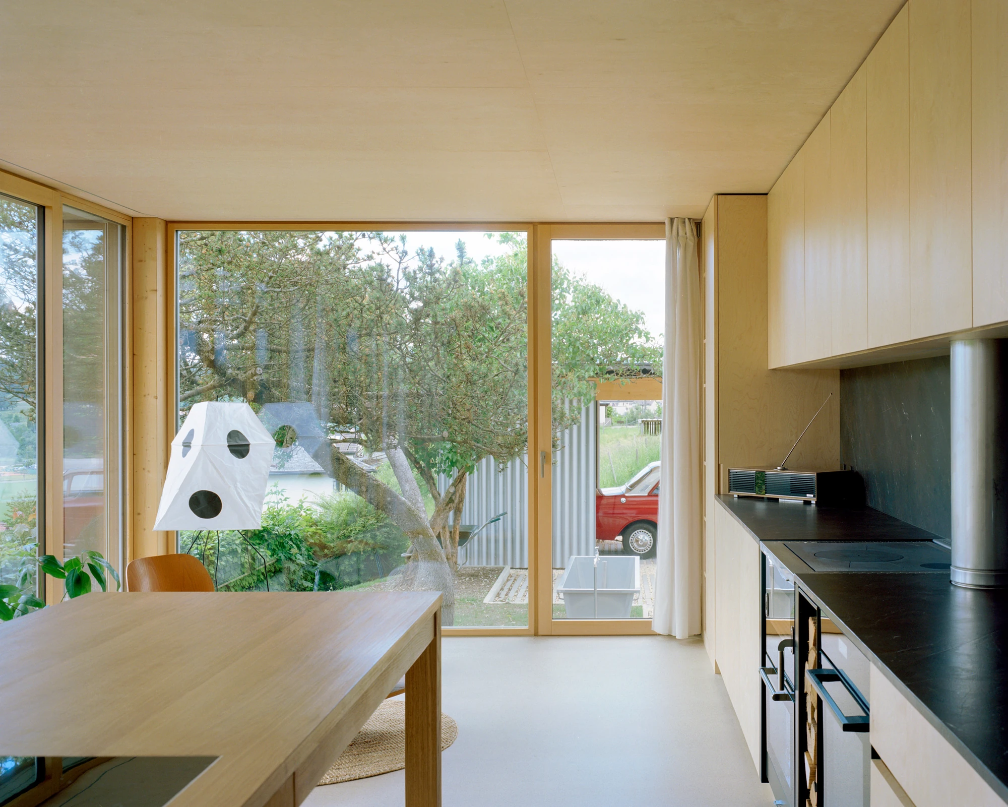 Plywood House by Charly Jolliet Architecte, photographed by Maxime Delvaux — Plywood lines the kitchen wall and ceiling, the only contrast coming from a warmer wood species at the table.