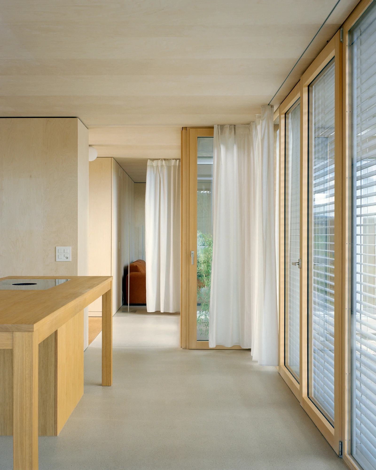 Plywood House by Charly Jolliet Architecte, photographed by Maxime Delvaux — The plywood lining runs continuously from the kitchen through to the living volume.