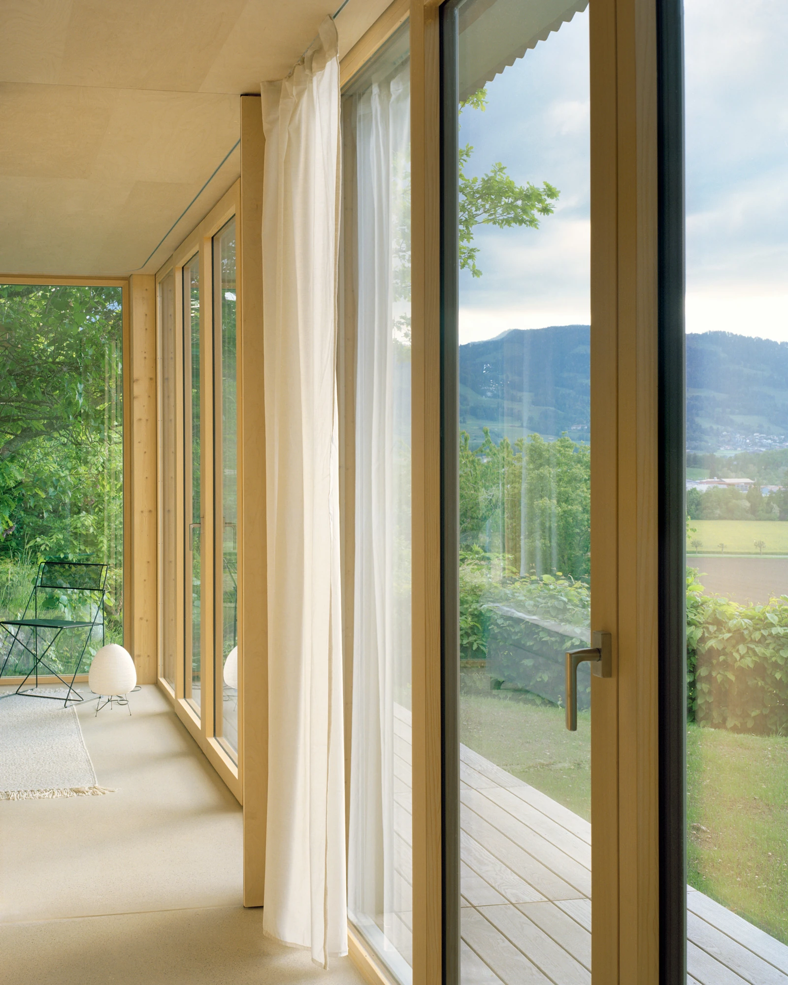 Plywood House by Charly Jolliet Architecte, photographed by Maxime Delvaux — A plywood wall meets the glazing, the interior held in a single continuous wood species.