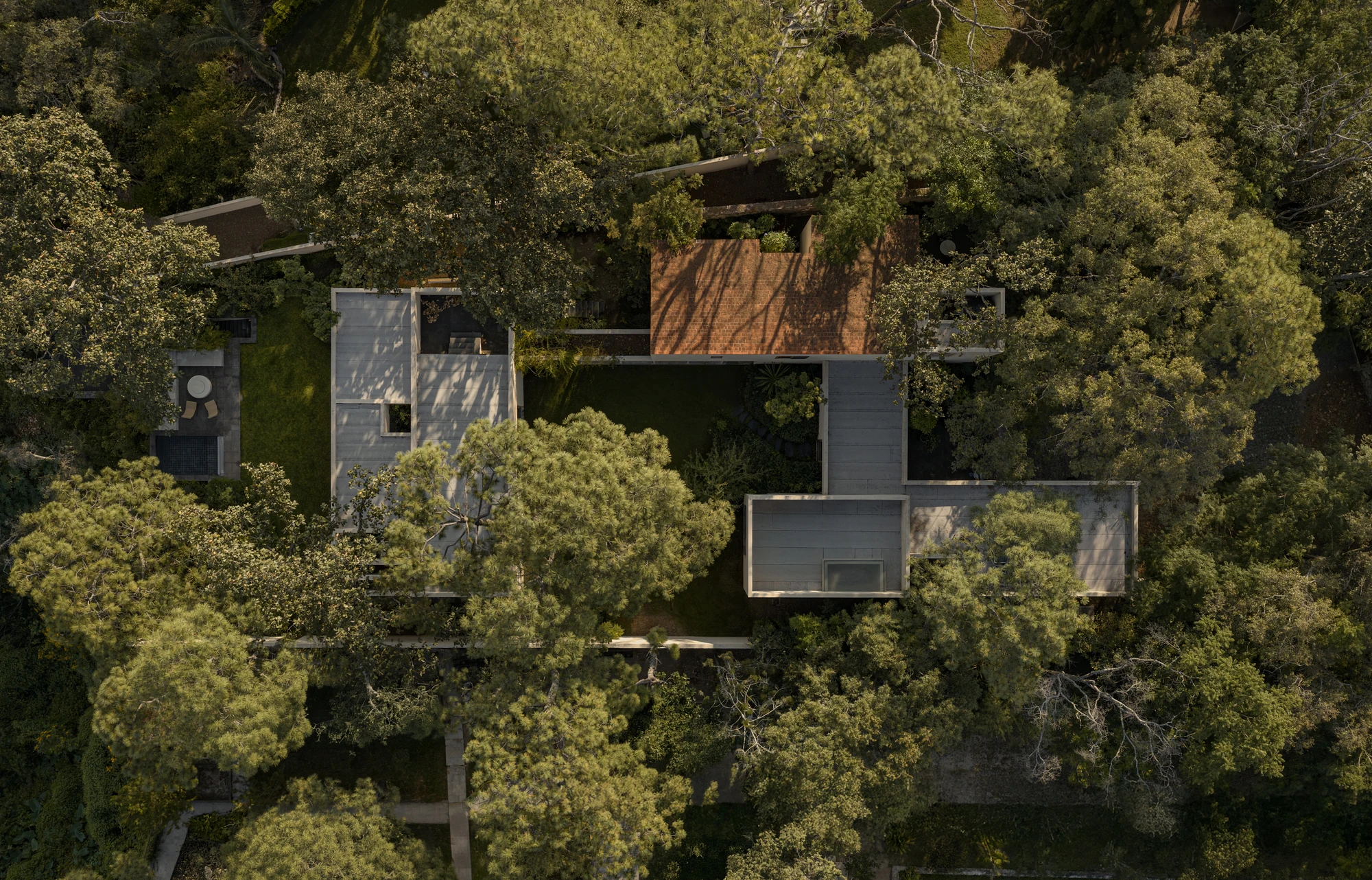 PRM39 by Ana Victoria Pérez-Gil | Saúl Figueroa, photographed by Funciono — A stone wall grounds the stucco volumes of PRM39 beneath the forest canopy.