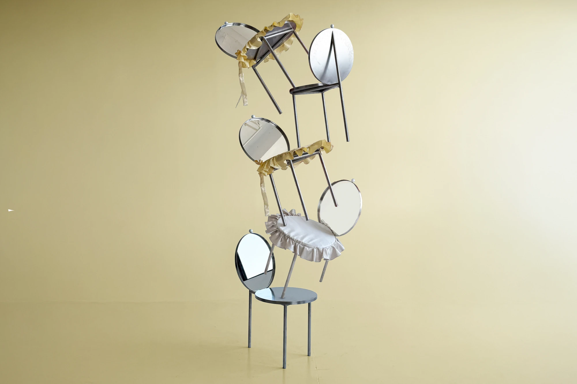 The Woman's Chair by Shushana Khachatrian, photographed by Katie Kutuzova — The chairs stacked into a precarious column, round mirror discs and frilled cushions catching the light.