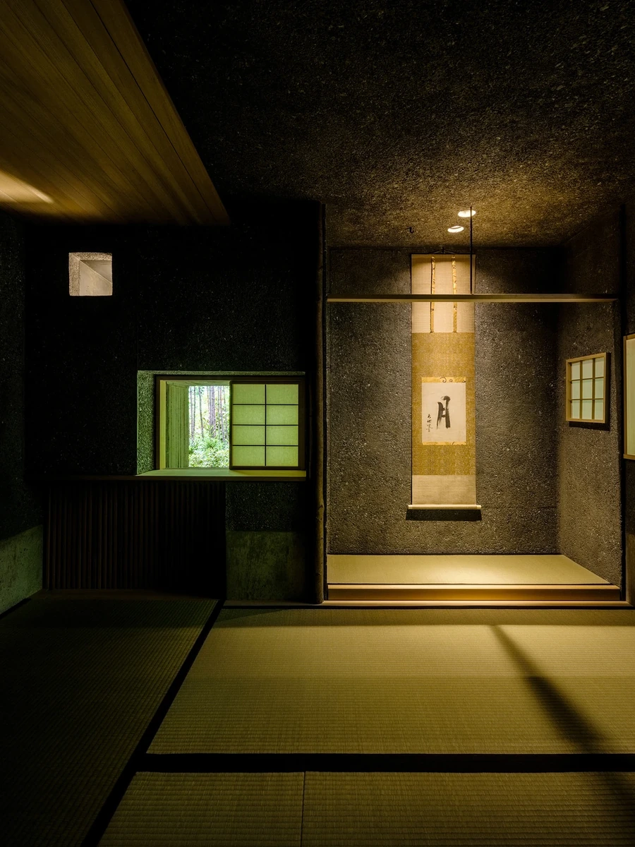 Konkuri-an by Teitakusubako, Yusuke Igarashi Architects, photographed by Kentaro Nemoto, Kazumasa Harada — An alcove set into the washed concrete wall of the tea room, framed by tatami and a timber ceiling, lit against the dark aggregate finish.