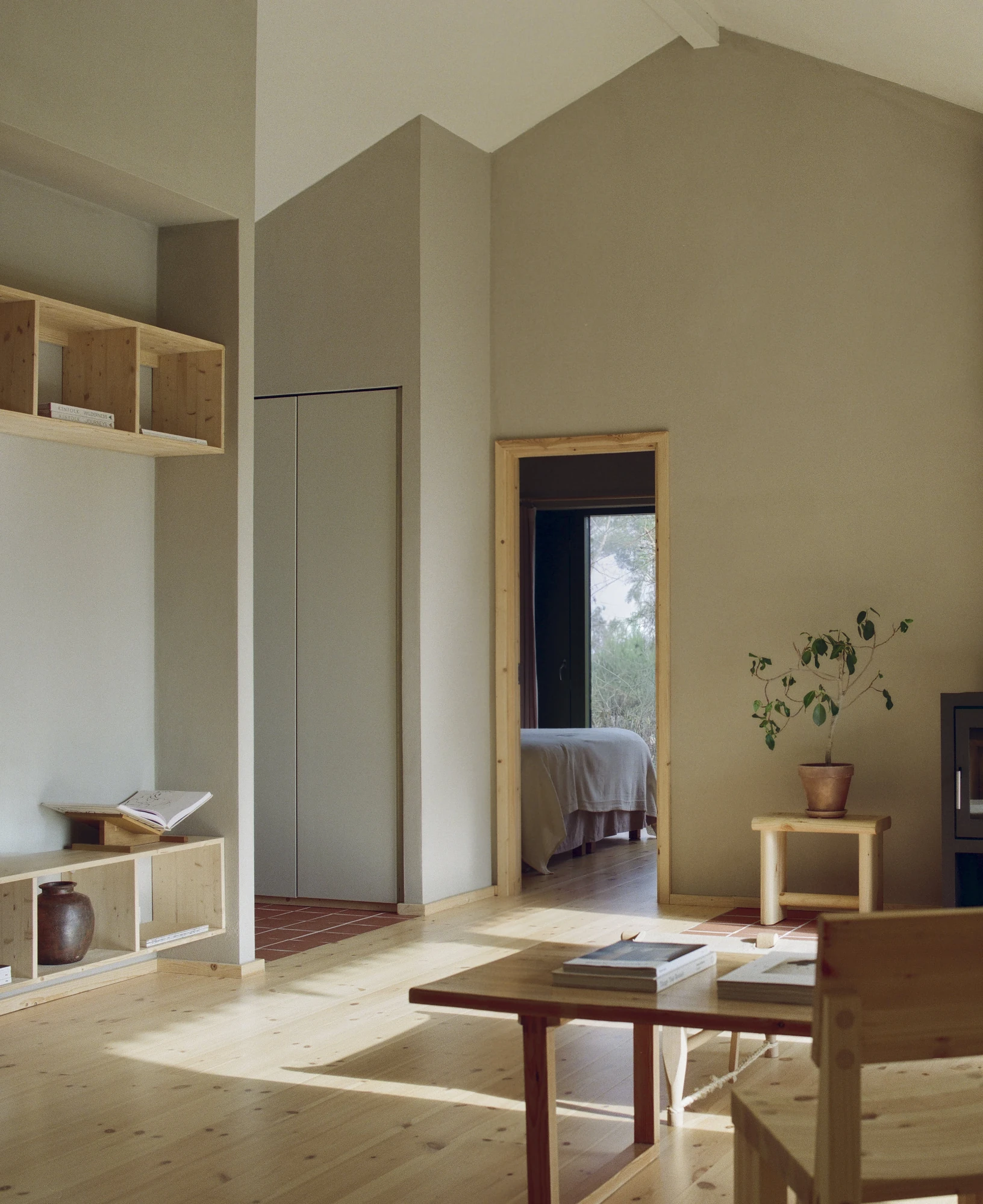 Stenkløvervej Vacation House by Studio Furö, photographed by Ditte Auguste Mørkholt — The living room looking towards built-in shelving and a doorway through to a bedroom.