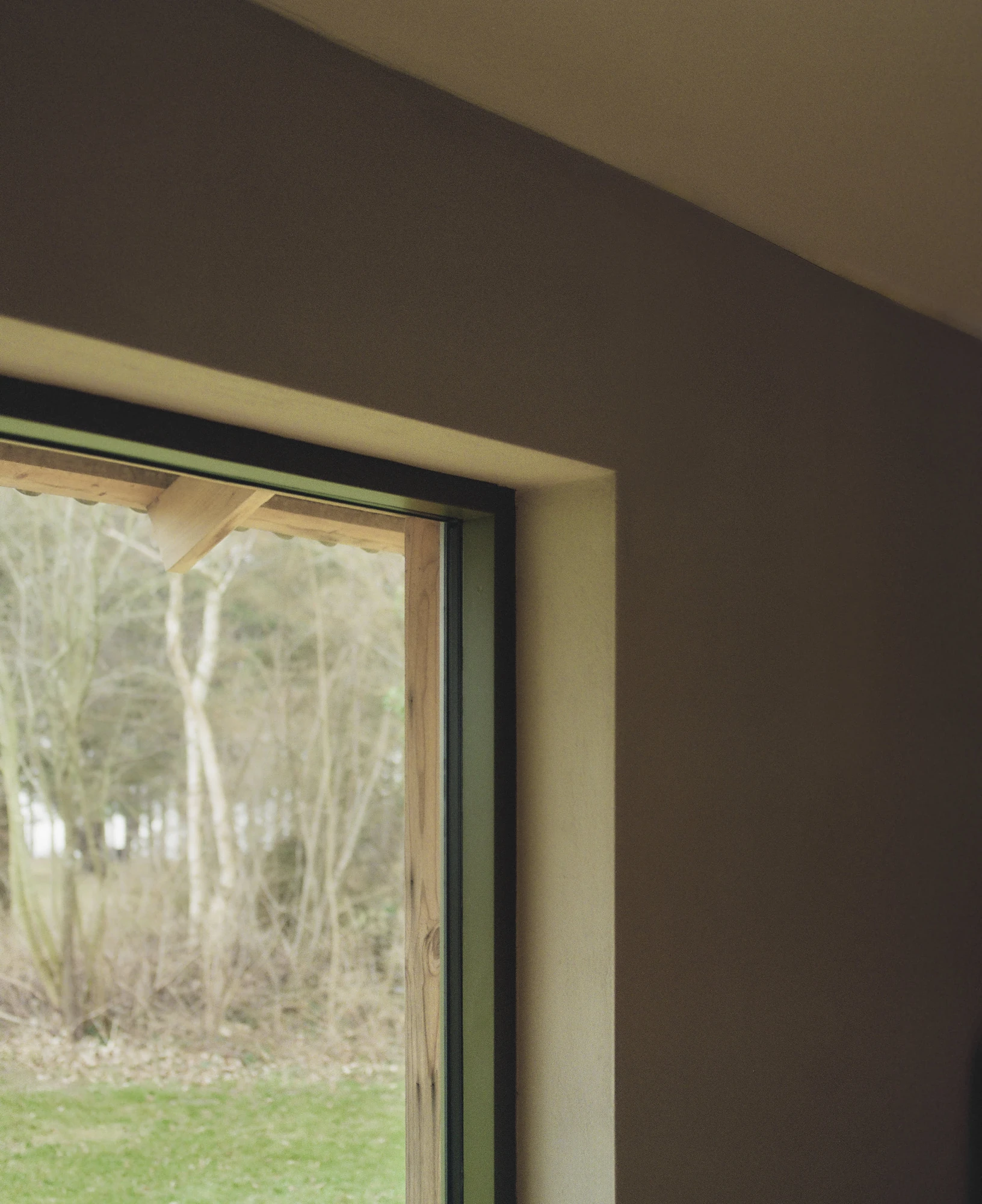 Stenkløvervej Vacation House by Studio Furö, photographed by Ditte Auguste Mørkholt — A window reveal set into a plastered wall, the ceiling sloping away above it.