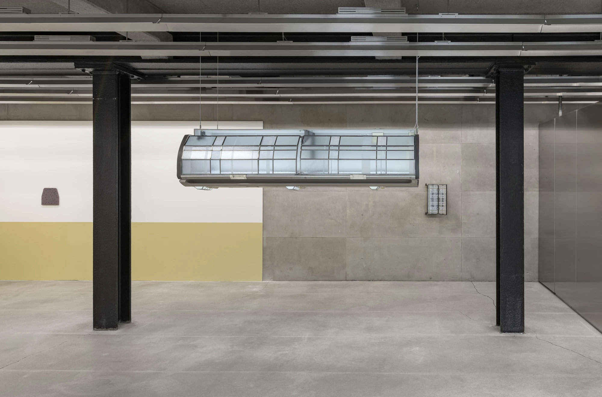 Addresses Without Names by Ju Young Kim, photographed by Dirk Tacke — Installation view with She slept better when nothing stayed still suspended between black steel columns and a small mauve fused-glass panel on the ochre-and-white wall.
