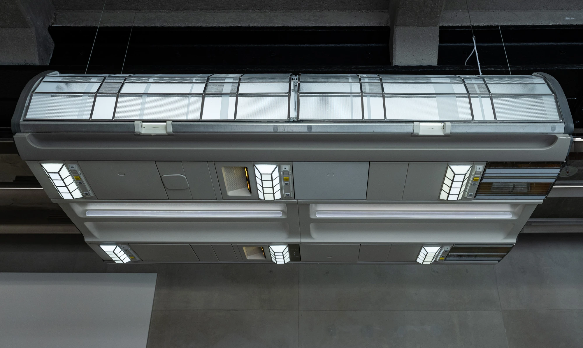 Addresses Without Names by Ju Young Kim, photographed by Dirk Tacke — The underside of She slept better when nothing stayed still, its bank of reading lights and numbered call buttons set into white leaded-glass panels.