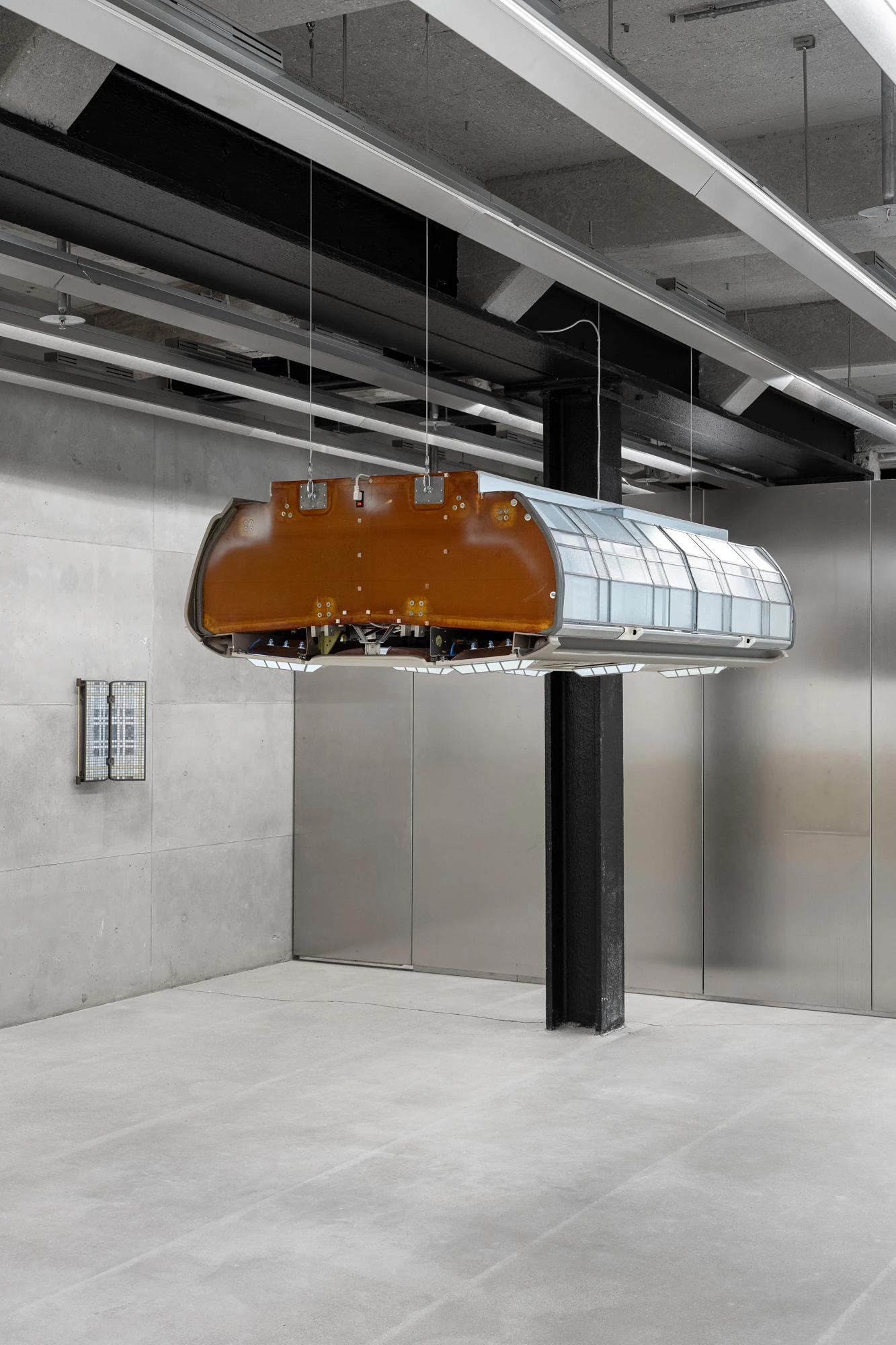 Addresses Without Names by Ju Young Kim, photographed by Dirk Tacke — She slept better when nothing stayed still seen end on, the amber-brown shell of the aircraft bin meeting its lit construction of leaded glass.