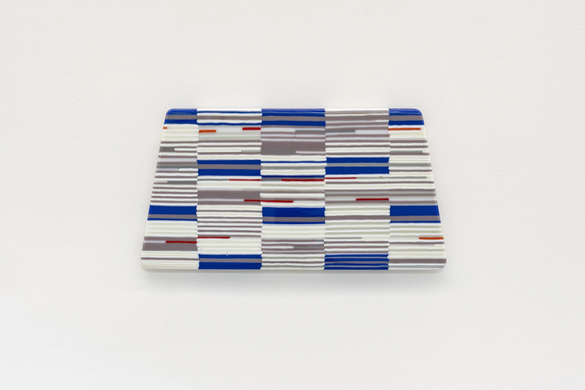 Addresses Without Names by Ju Young Kim, photographed by Dirk Tacke — She remembered exactly what it felt like, 2026, a horizontal fused-glass panel of hand-cut strips in blue, grey and white with red accents, woven like seat fabric, 22.5 x 43 x 1.2 cm.