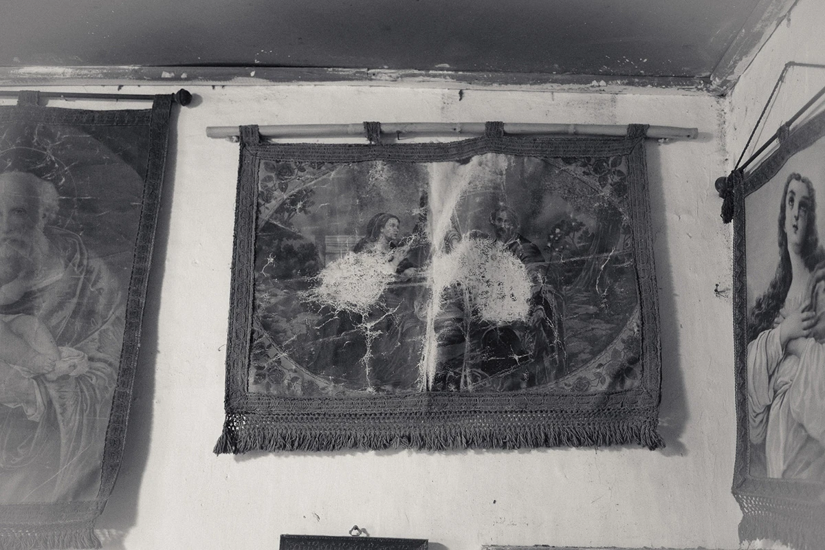 An Island Within the Island by succco, photographed by succco — Old, water-stained devotional tapestries and framed religious prints hang near the ceiling of a whitewashed room.