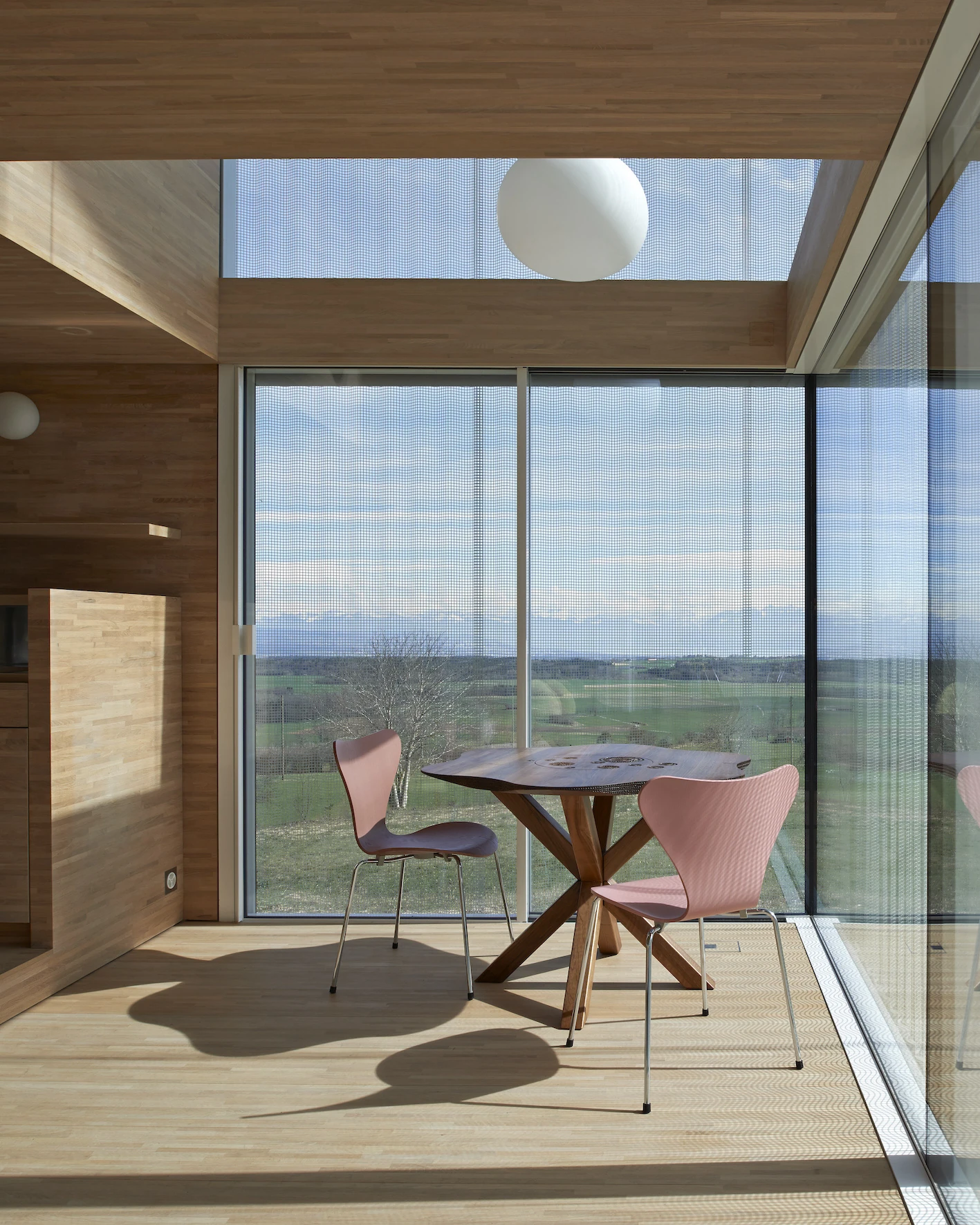 Writers' Cabins at the Jan Michalski Foundation by Kengo Kuma, ELEMENTAL, MK27 and Others, photographed by Leo Fabrizio, Tonatiuh Ambrosetti — Inside bonnet's cabin, light oak lines the double-height room while a mesh scrim veils the floor-to-ceiling…