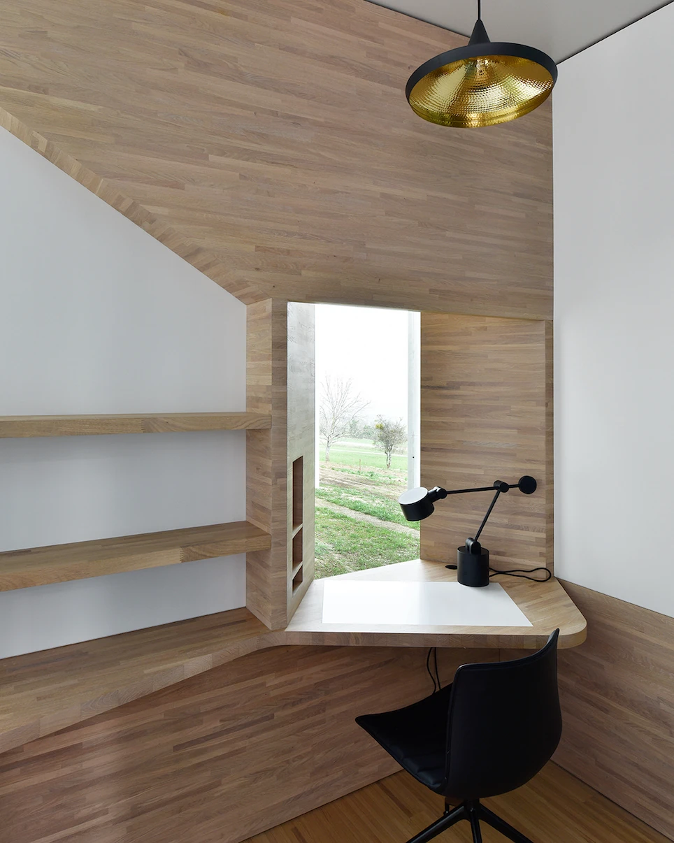 Writers' Cabins at the Jan Michalski Foundation by Kengo Kuma, ELEMENTAL, MK27 and Others, photographed by Leo Fabrizio, Tonatiuh Ambrosetti — A writing nook in Mangeat-Wahlen's cabin folds oak across its angled walls and ceiling, a corner desk and…