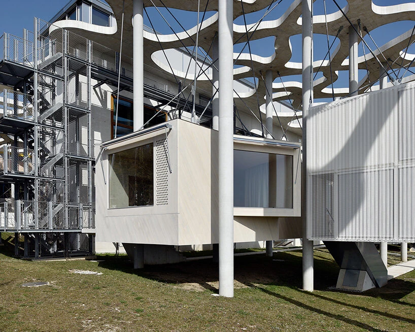 Writers' Cabins at the Jan Michalski Foundation by Kengo Kuma, ELEMENTAL, MK27 and Others, photographed by Leo Fabrizio, Tonatiuh Ambrosetti — Schaub Zwicky's accessible cabin, clad in pale accoya with a perforated panel and a wraparound window,…