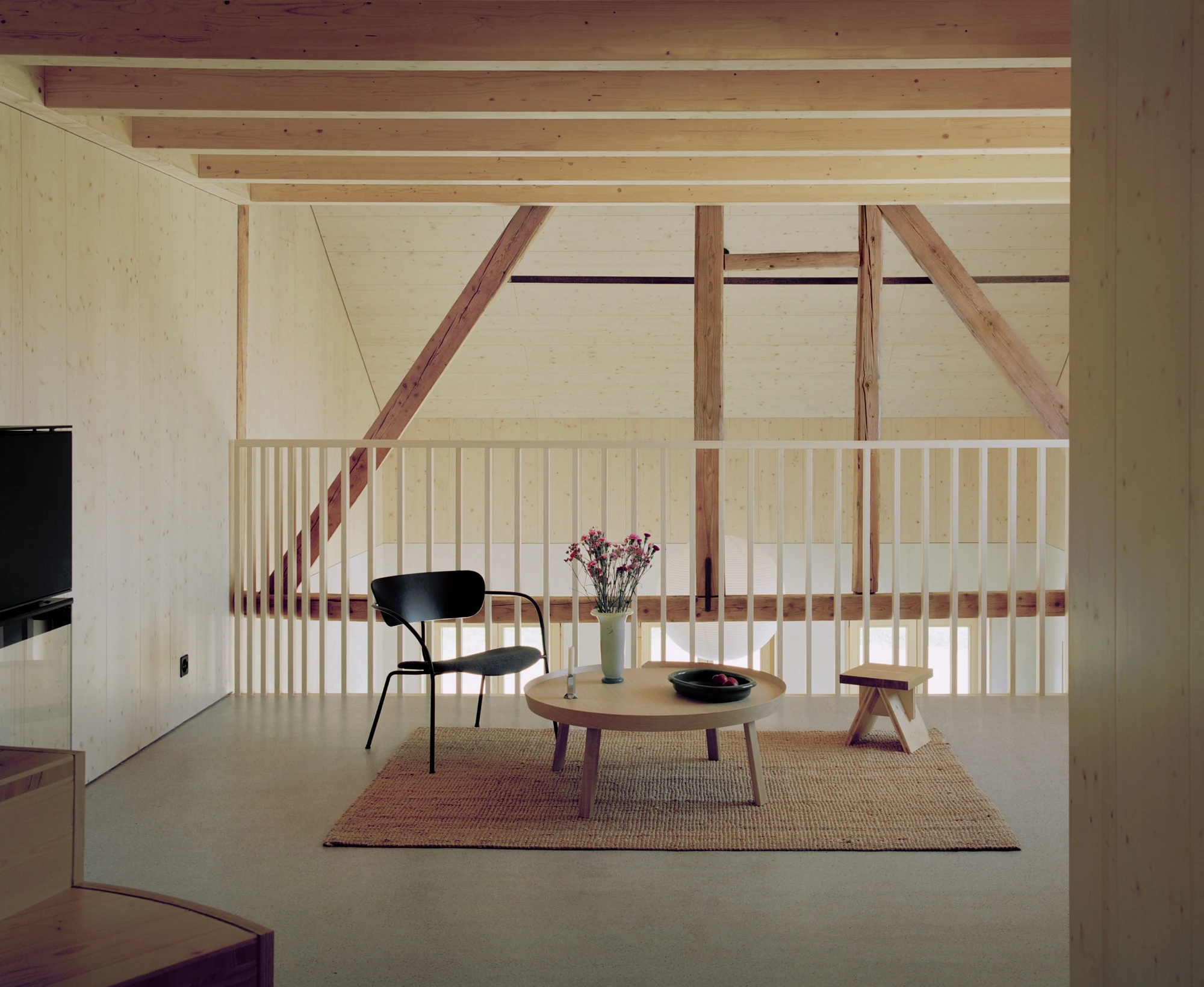 Conversion of a Farmhouse into Six Apartments by Noue Studio, photographed by Willem Pab — The upper living space under exposed timber beams, edged by a thin balustrade.