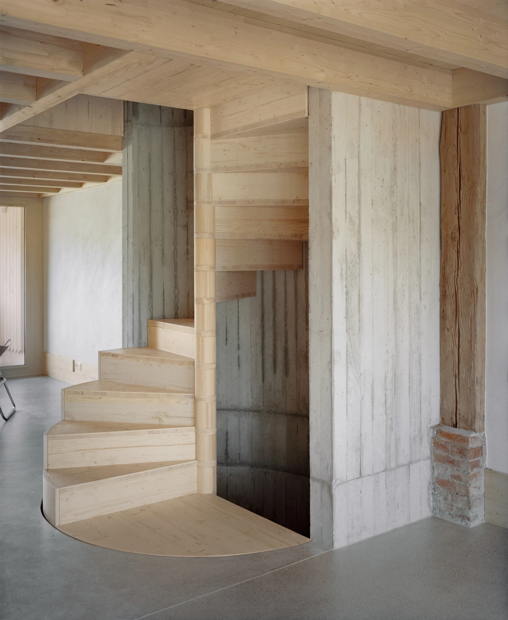 Conversion of a Farmhouse into Six Apartments by Noue Studio, photographed by Willem Pab — A winding timber stair rising against a raw structural wall.