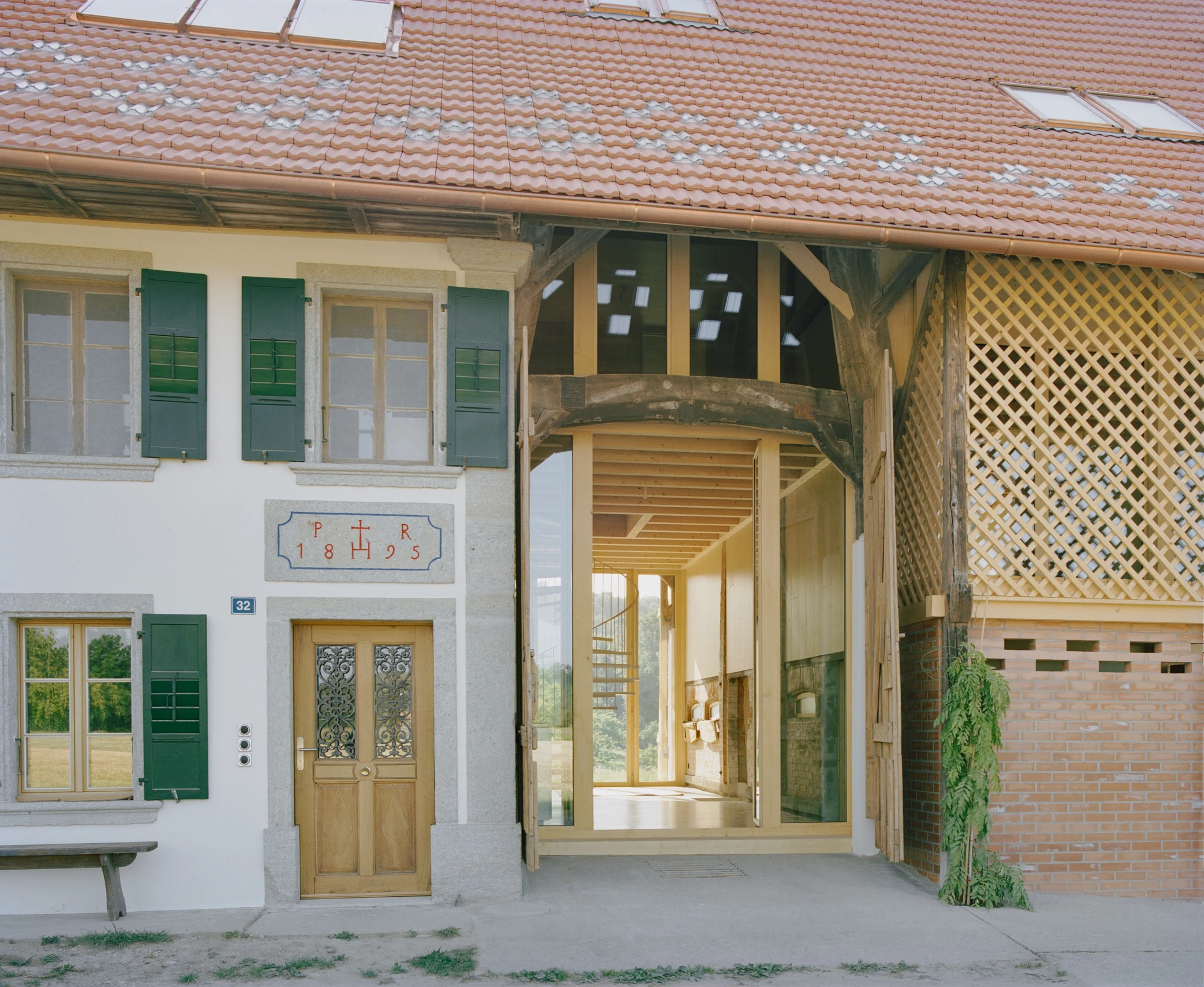 Conversion of a Farmhouse into Six Apartments by Noue Studio, photographed by Willem Pab — The street facade at the entry, an old doorway beside the new glazed passage.