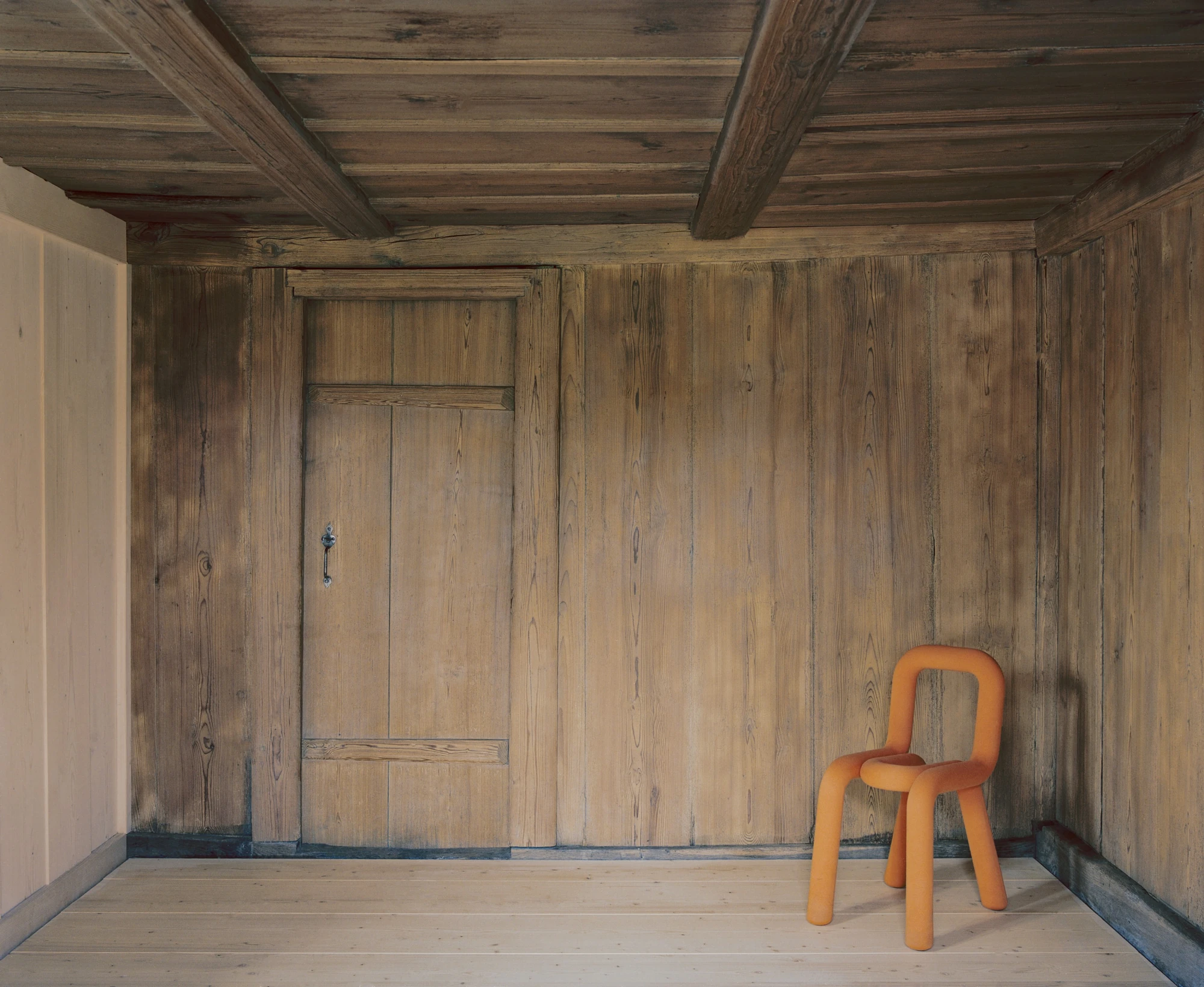 Conversion of a Farmhouse into Six Apartments by Noue Studio, photographed by Willem Pab — A room lined in old timber boards with a new plank floor and a single chair in the corner.