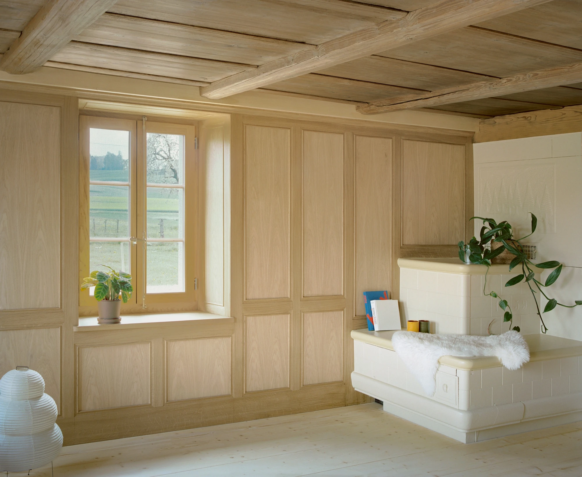 Conversion of a Farmhouse into Six Apartments by Noue Studio, photographed by Willem Pab — An old panelled room with a corner stove beside a window onto the fields.