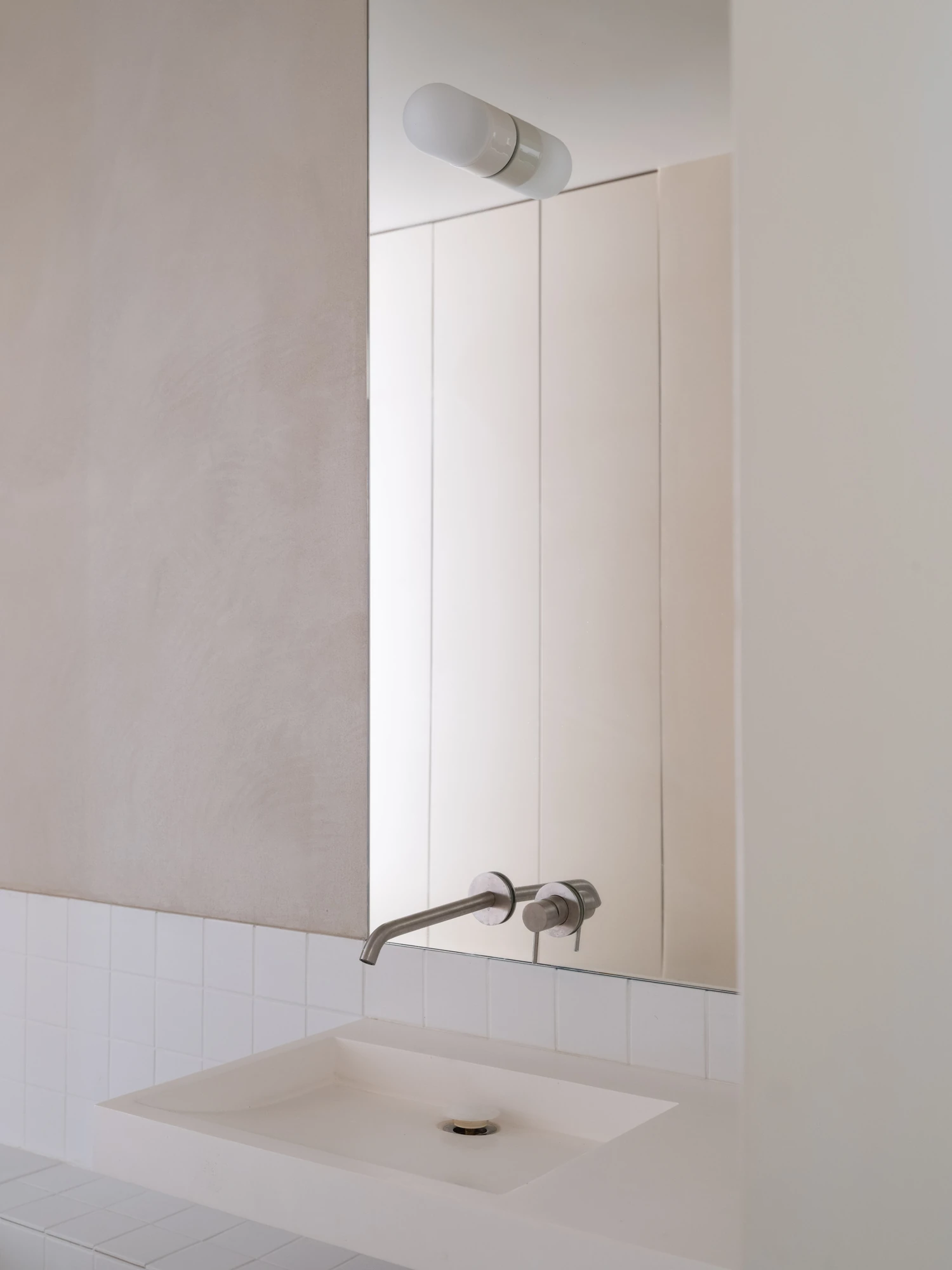 Farmhouse Renovation by Atelier AJO, photographed by Sandrine Iratçabal — A washbasin below a wall-mounted tap and a tall mirror set into the wall.