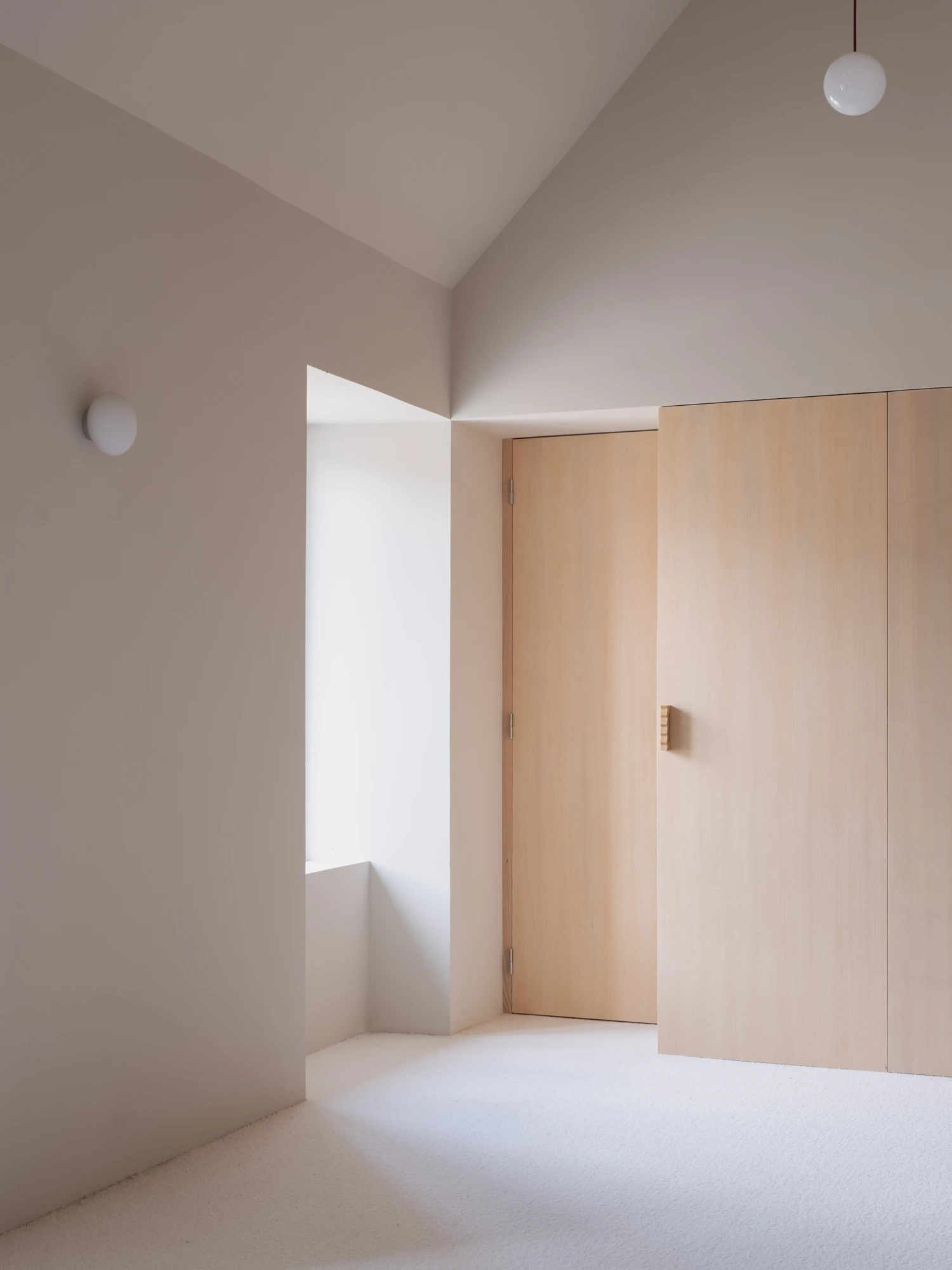 Farmhouse Renovation by Atelier AJO, photographed by Sandrine Iratçabal — A room under the roof slope with a window recess and a run of built-in cabinetry.