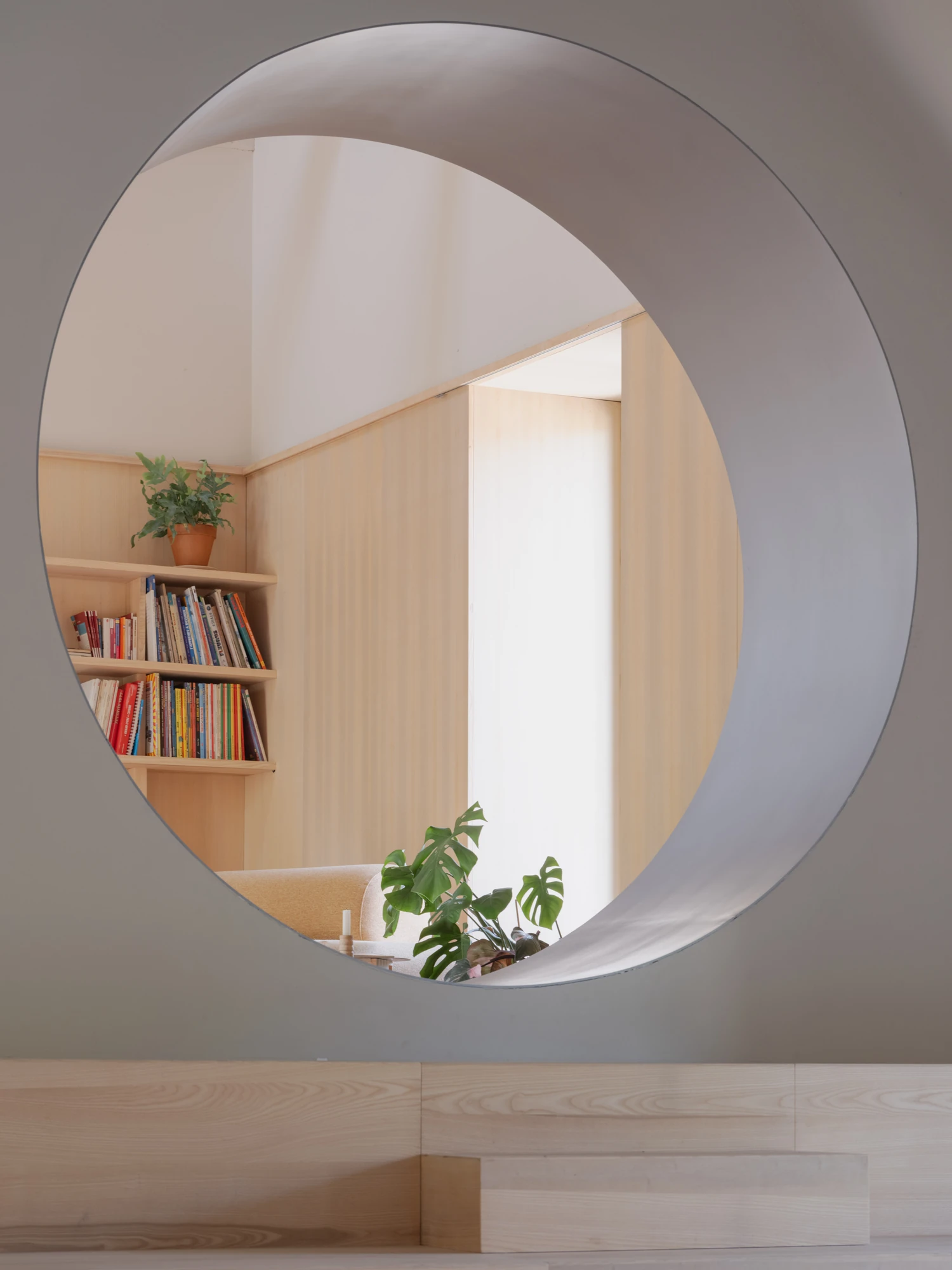 Farmhouse Renovation by Atelier AJO, photographed by Sandrine Iratçabal — The circular opening looking through to the library wall and its shelves of books.