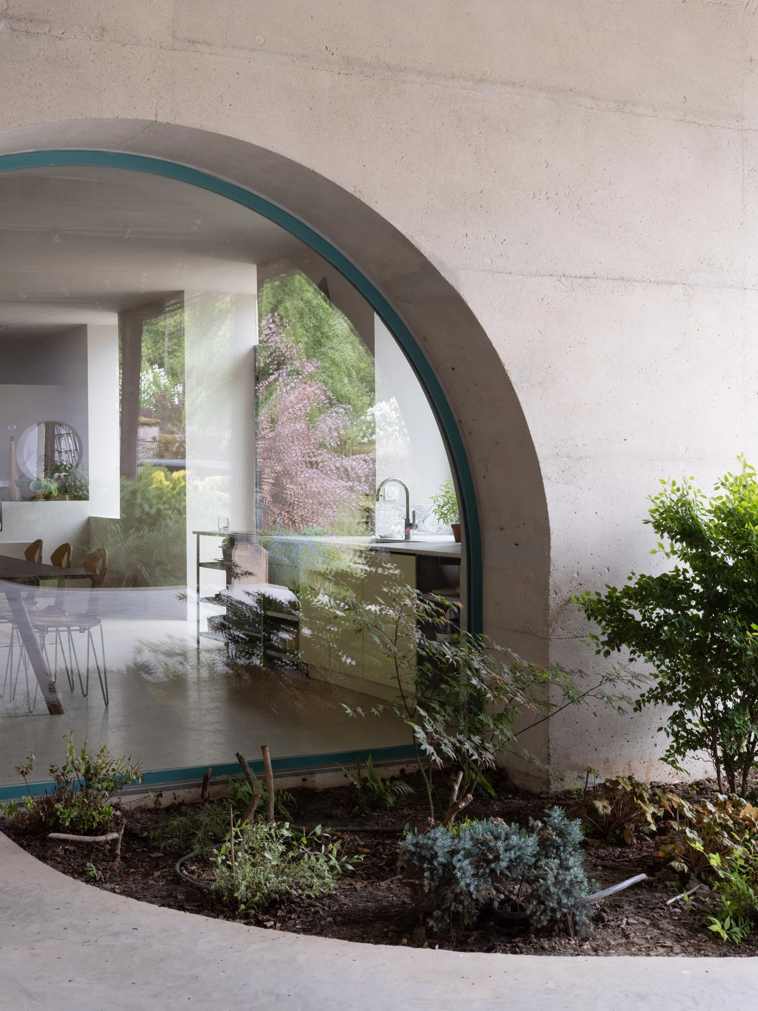Farmhouse Renovation by Atelier AJO, photographed by Sandrine Iratçabal — The arched glazed opening seen from the planted barn, its curved head set into the wall.