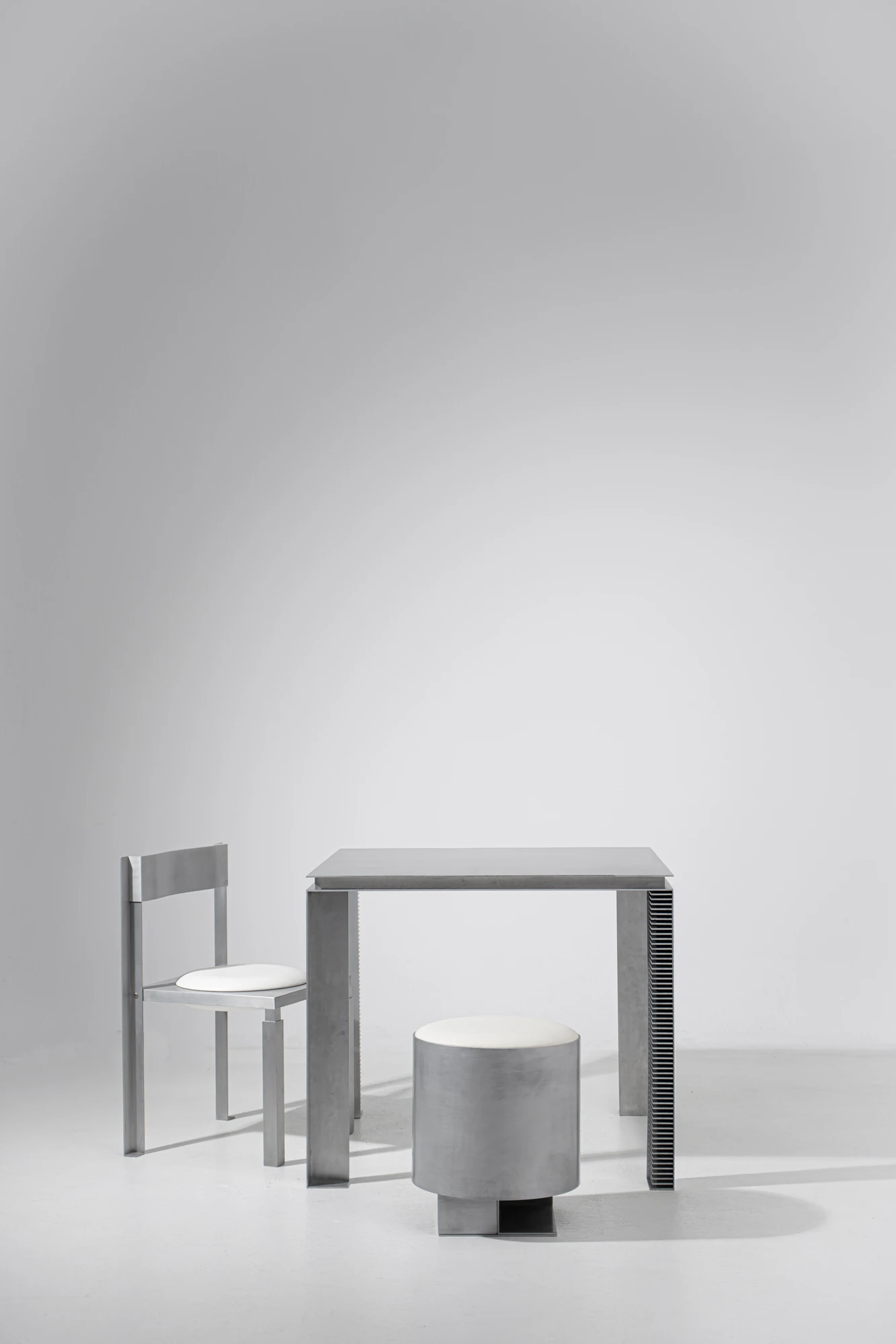 Strut Collection by YET. Design Studio, photographed by Kaan Bayoglu — The Strut Chair, Table and Pouf arranged together as a group, seen straight on against a plain studio backdrop.