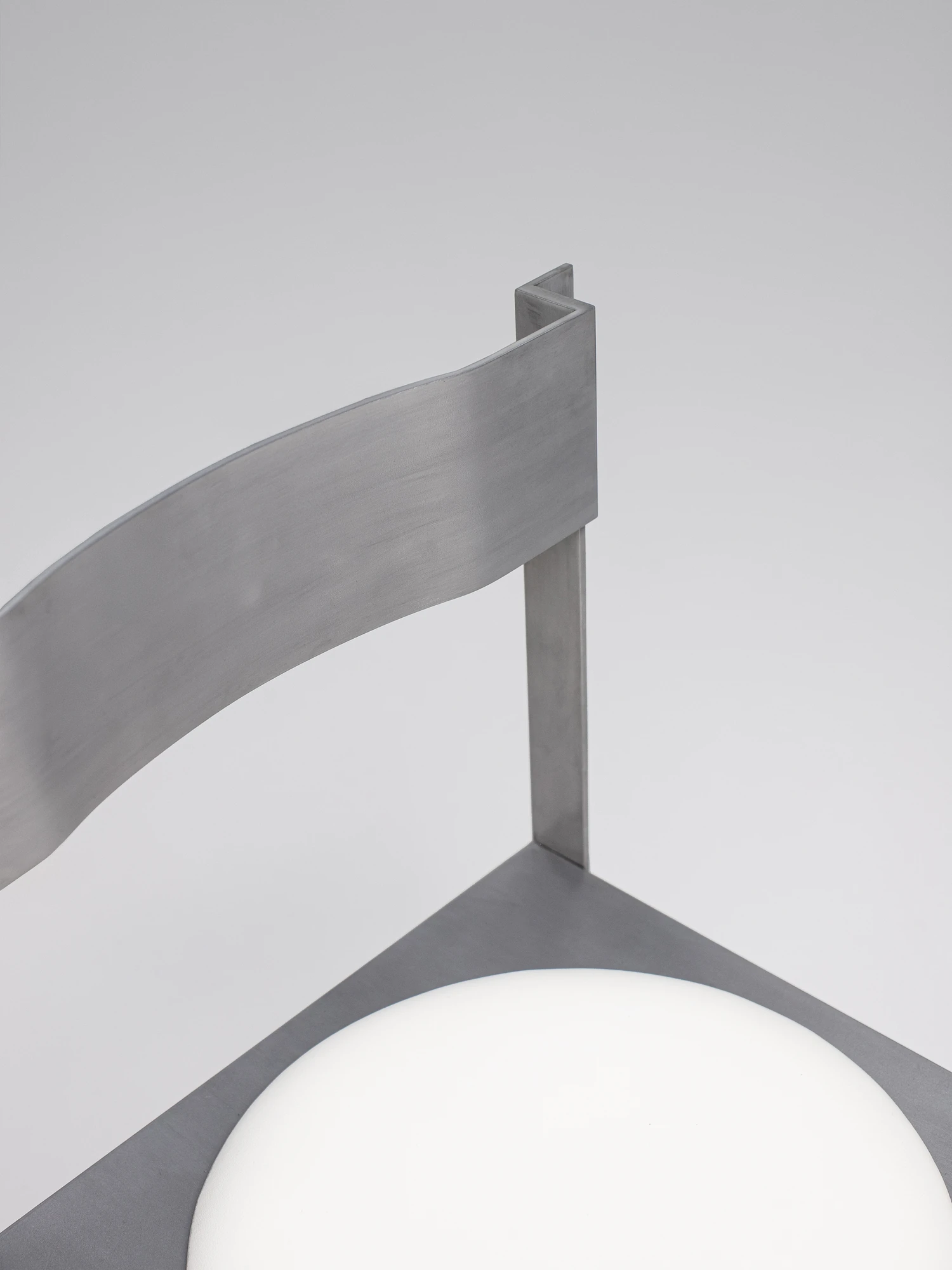 Strut Collection by YET. Design Studio, photographed by Kaan Bayoglu — A close view of the Strut Chair from behind, its curved backrest meeting a slim vertical post above the circular seat.