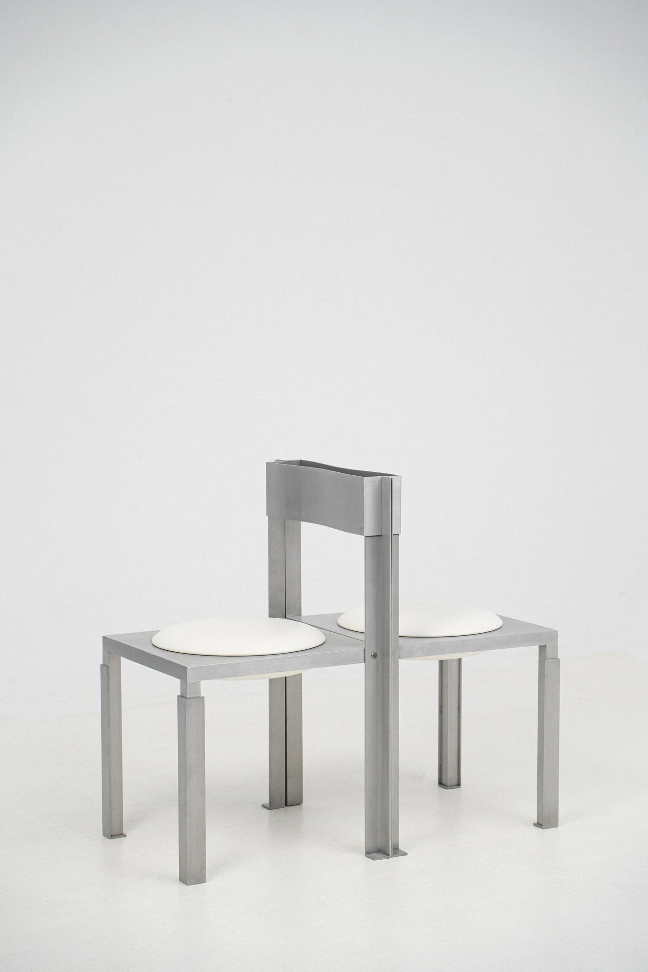 Strut Collection by YET. Design Studio, photographed by Kaan Bayoglu — Two Strut Chairs set back to back, their backrests side by side and their circular seats facing opposite ways.