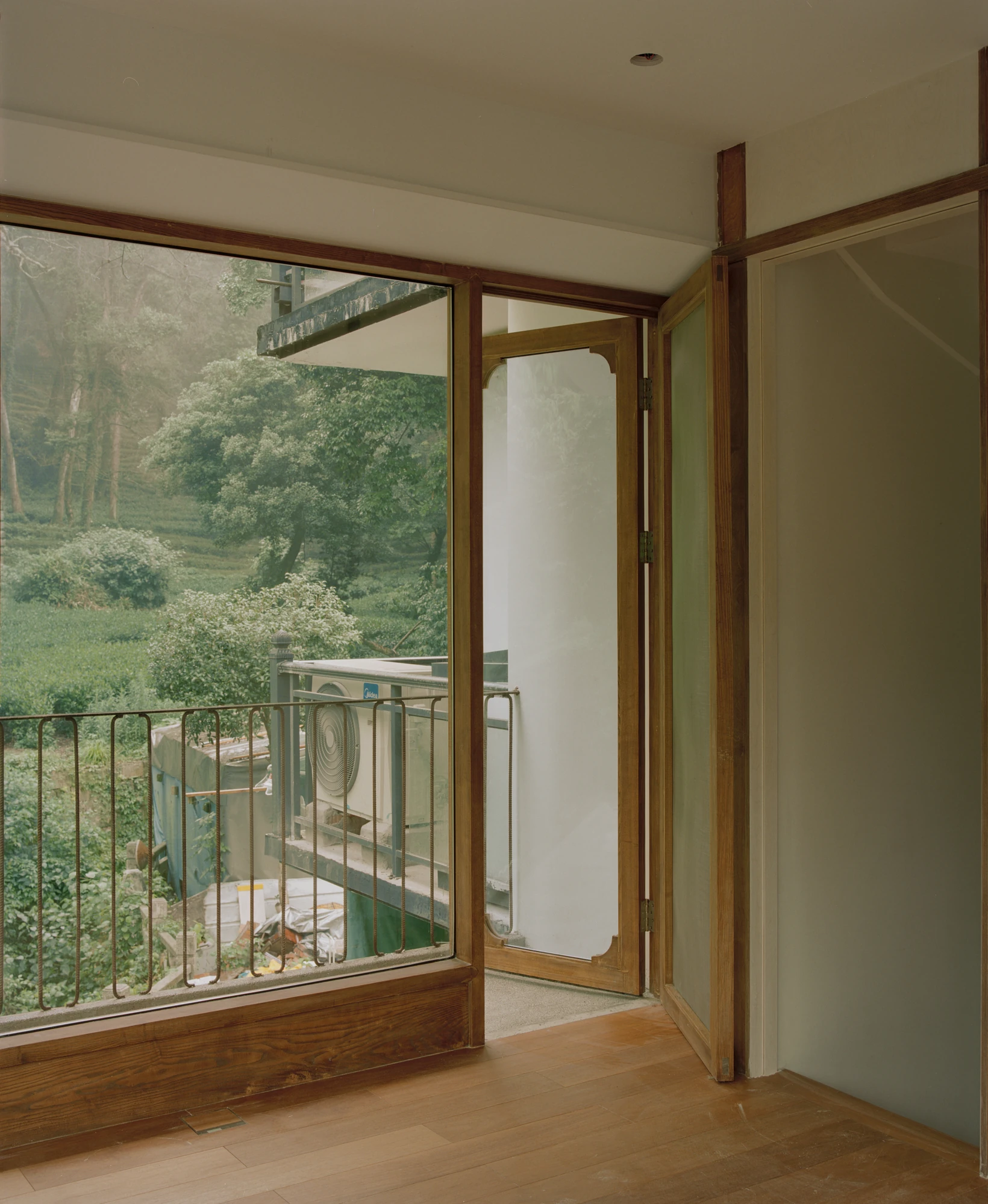 L Hermit House II by Common Wonder, photographed by Willem Pab, Eva Candela — A glazed opening and open timber door looking out to the tea fields.