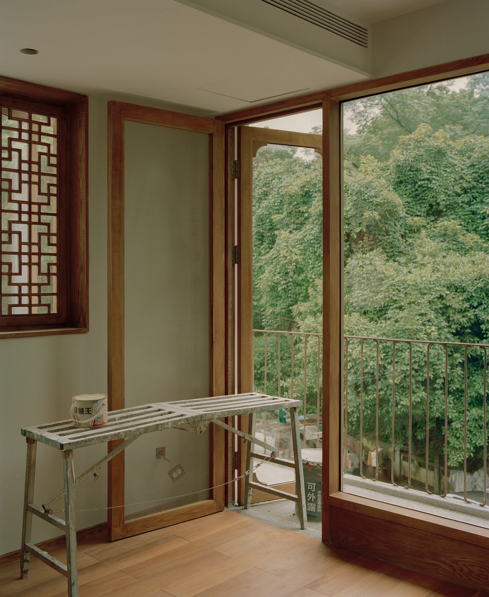 L Hermit House II by Common Wonder, photographed by Willem Pab, Eva Candela — An interior corner where a lattice window meets a timber-framed door standing open to the balcony.