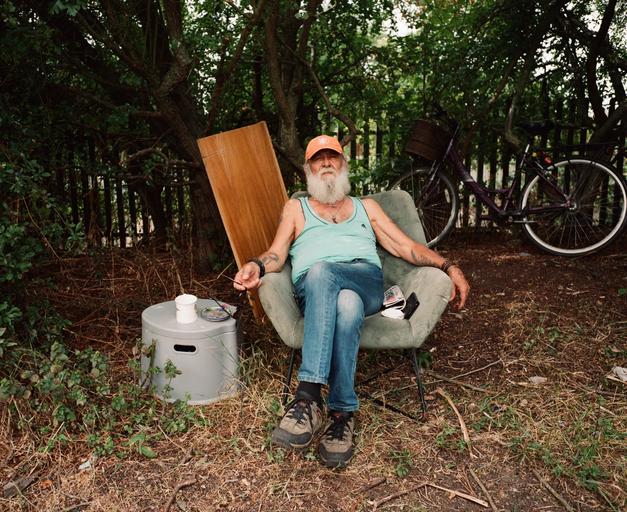 Along the River Lea by Mattia Corato, photographed by Mattia Corato — Osman, seated in an armchair outdoors among trees.