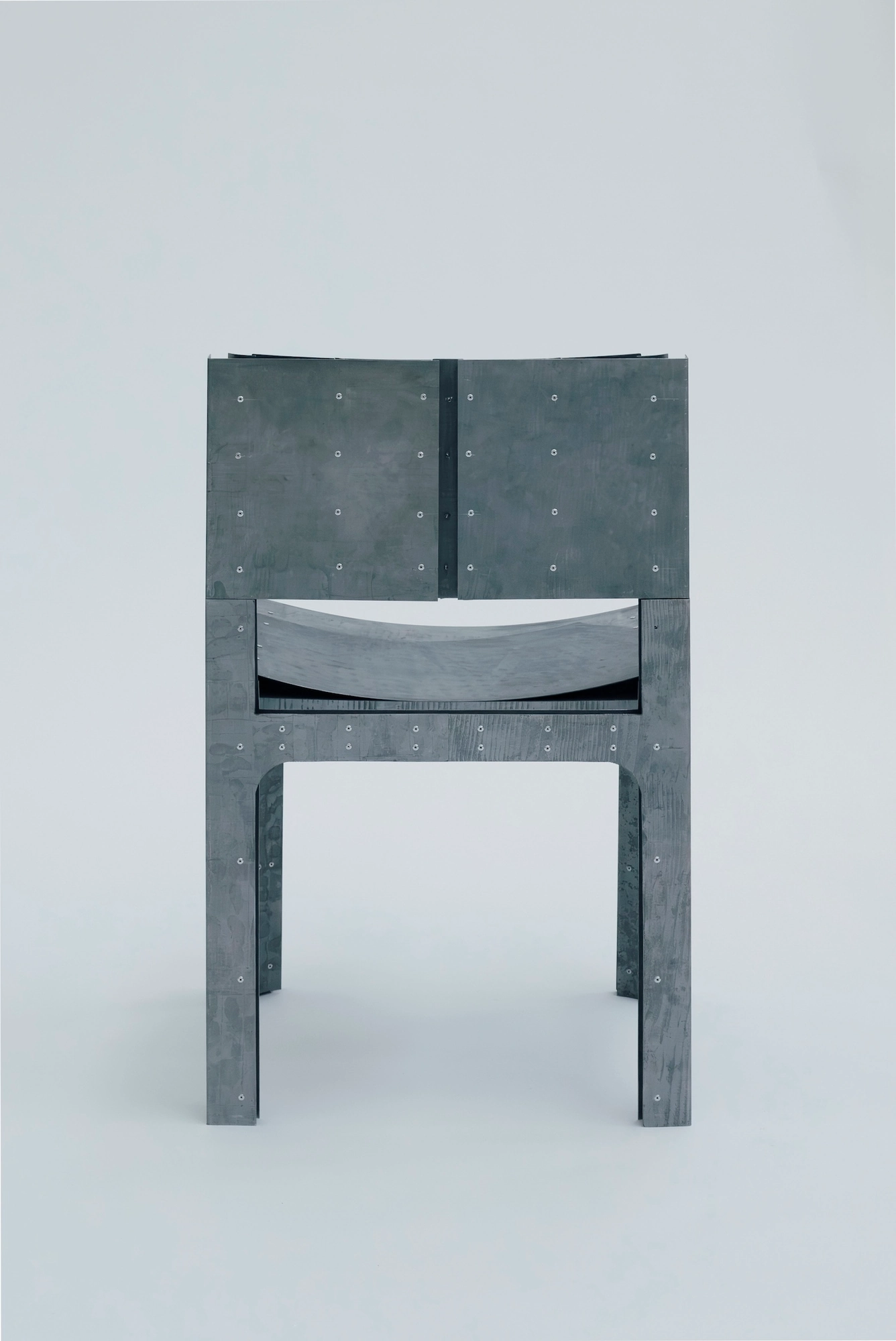 Trauer Tragen, Carrying Grief by Antonia Fischer, photographed by Maya Matsuura, Antonia Fischer — The chair straight on against a grey studio backdrop, the two back plates set above the seat and legs.