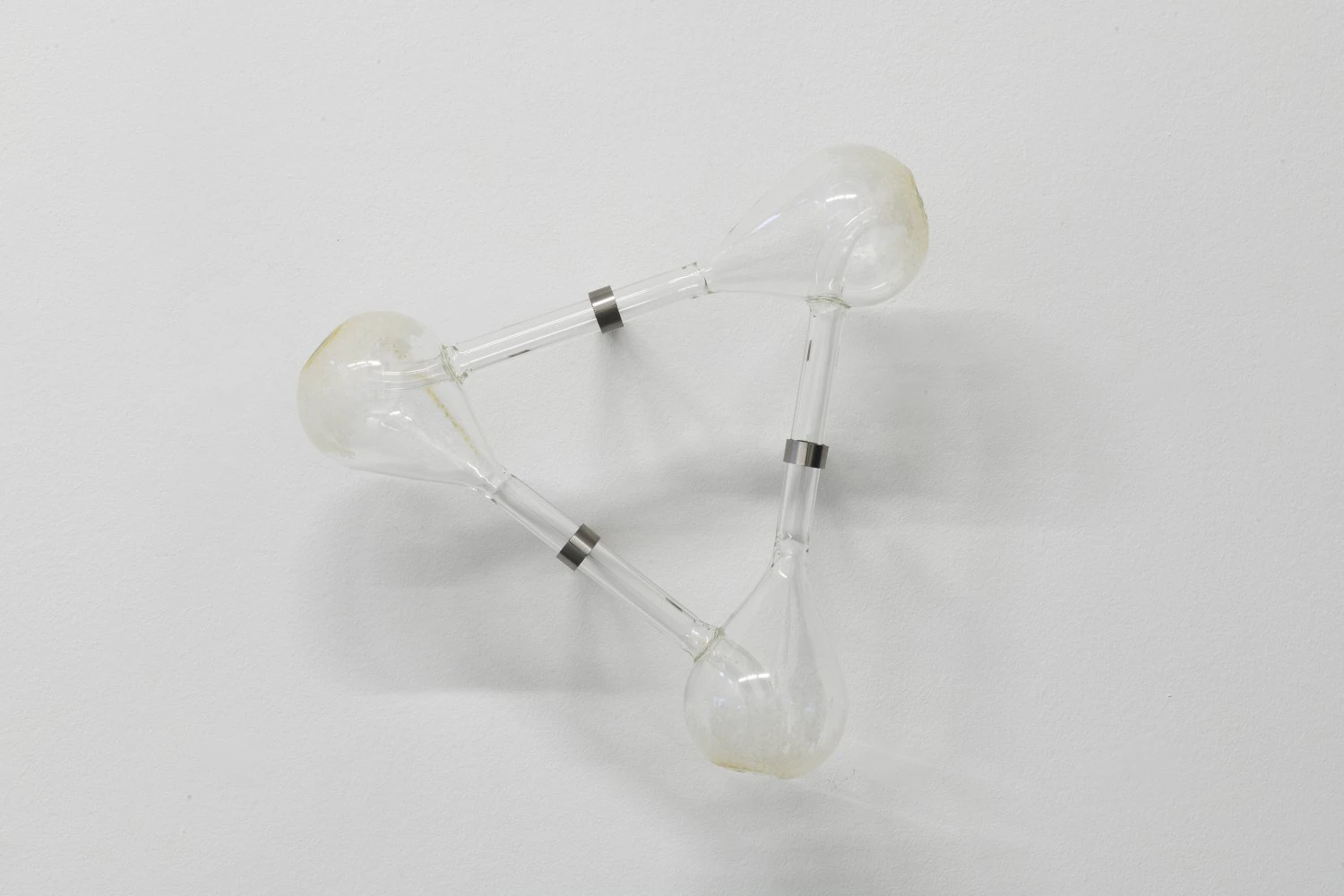 Half-Life of Grace by Jeremy Shaw, photographed by Stefan Korte — Even the Most Ruinous Eventually Leads You Home, three glass chambers connected by clear tubes and stainless steel bands.