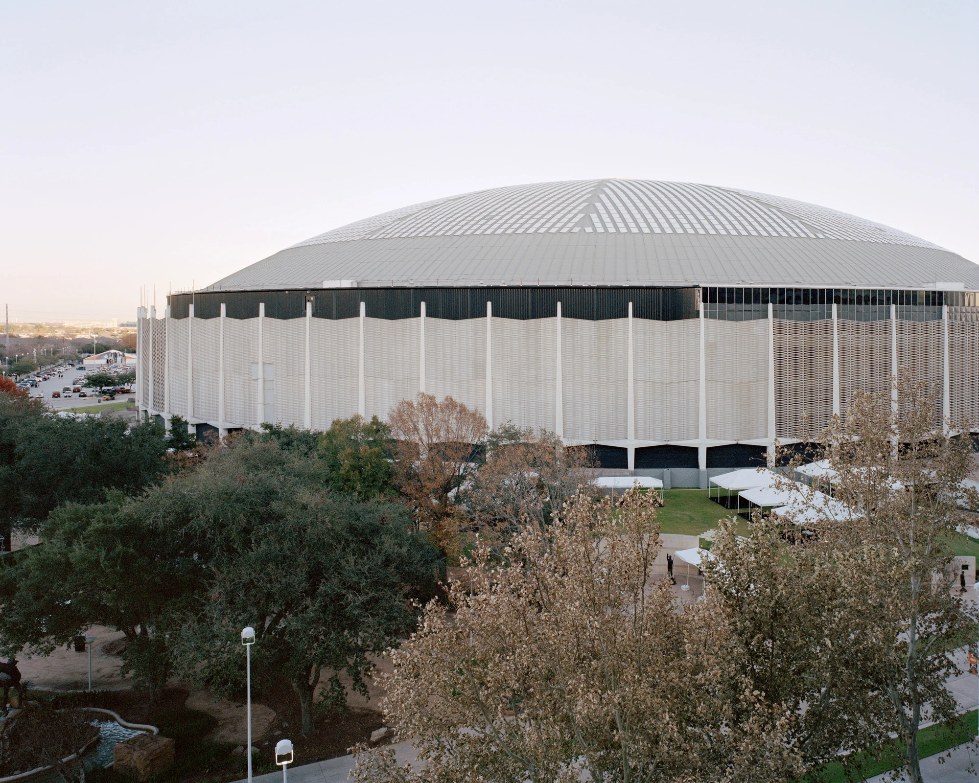 Houston, Untitled by Rory Gardiner, photographed by Rory Gardiner — 29.685405, -95.409647: a large domed stadium seen across trees.