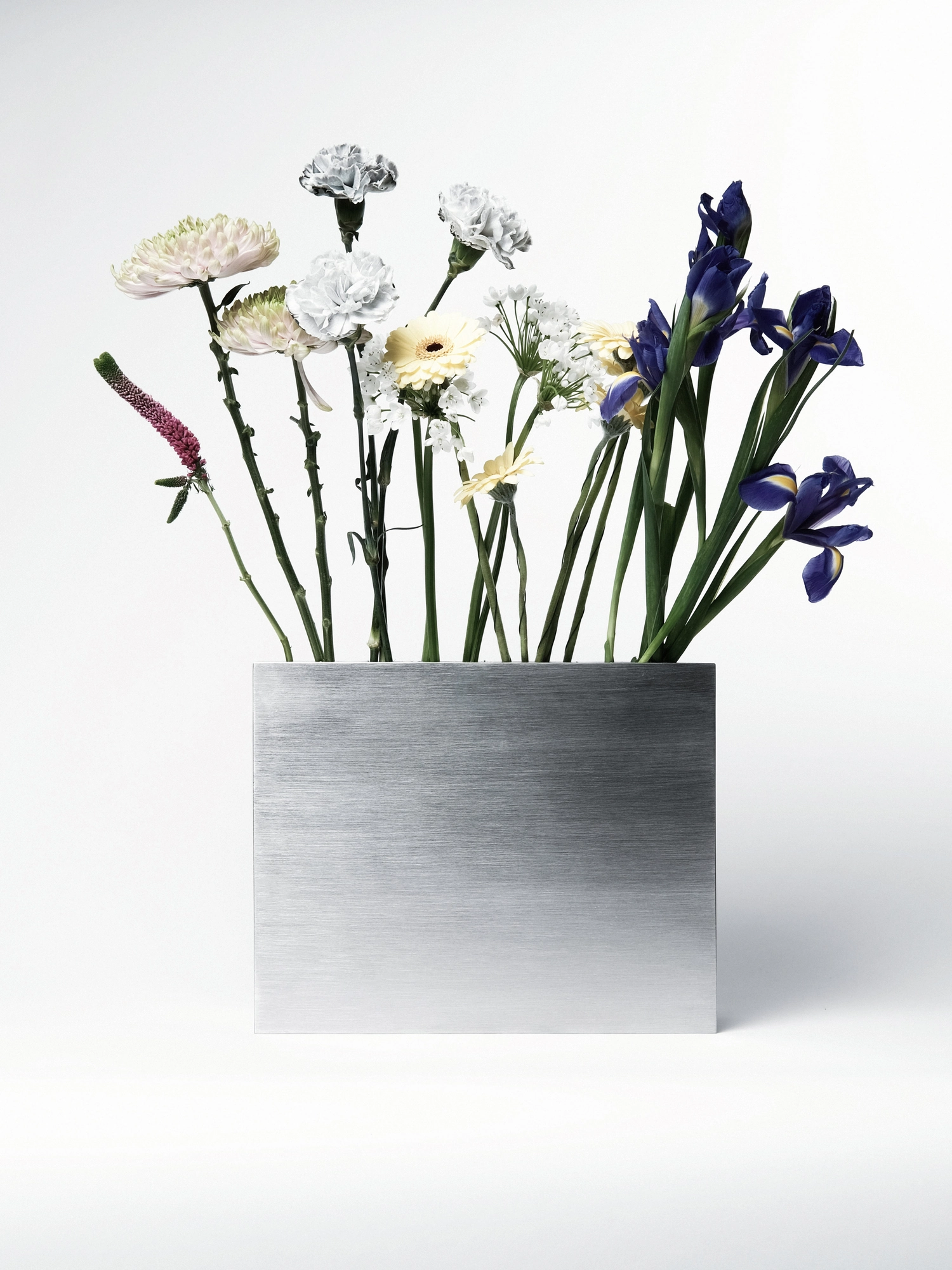 Apropos VASE-21 by Non-Objective, photographed by Elena Gavrilenko — VASE-21 filled with a mixed arrangement, stems fanning out above the stainless steel block seen head-on