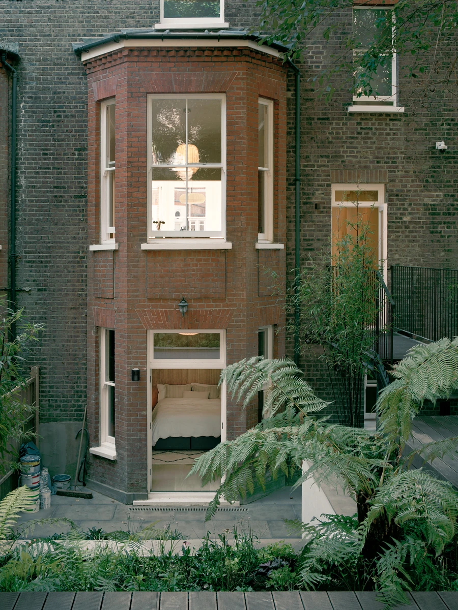 Hampstead House by Twelve Forty One, photographed by Willem Pab — The rear facade cropped to the bay, a garden-level bedroom showing through its glazed door.