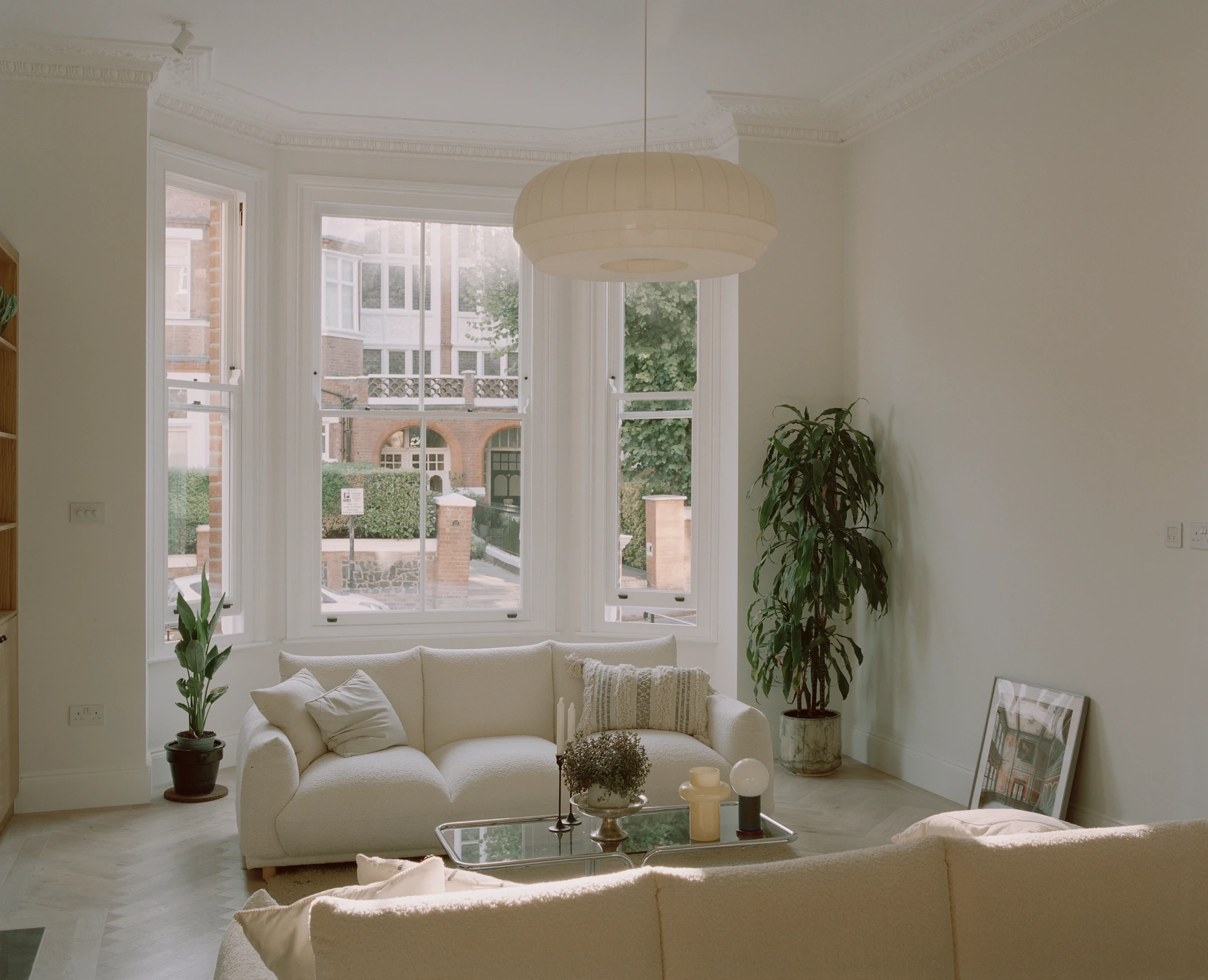 Hampstead House by Twelve Forty One, photographed by Willem Pab — The living room from within, two pale sofas and a low table under the bay window with the terraces beyond.