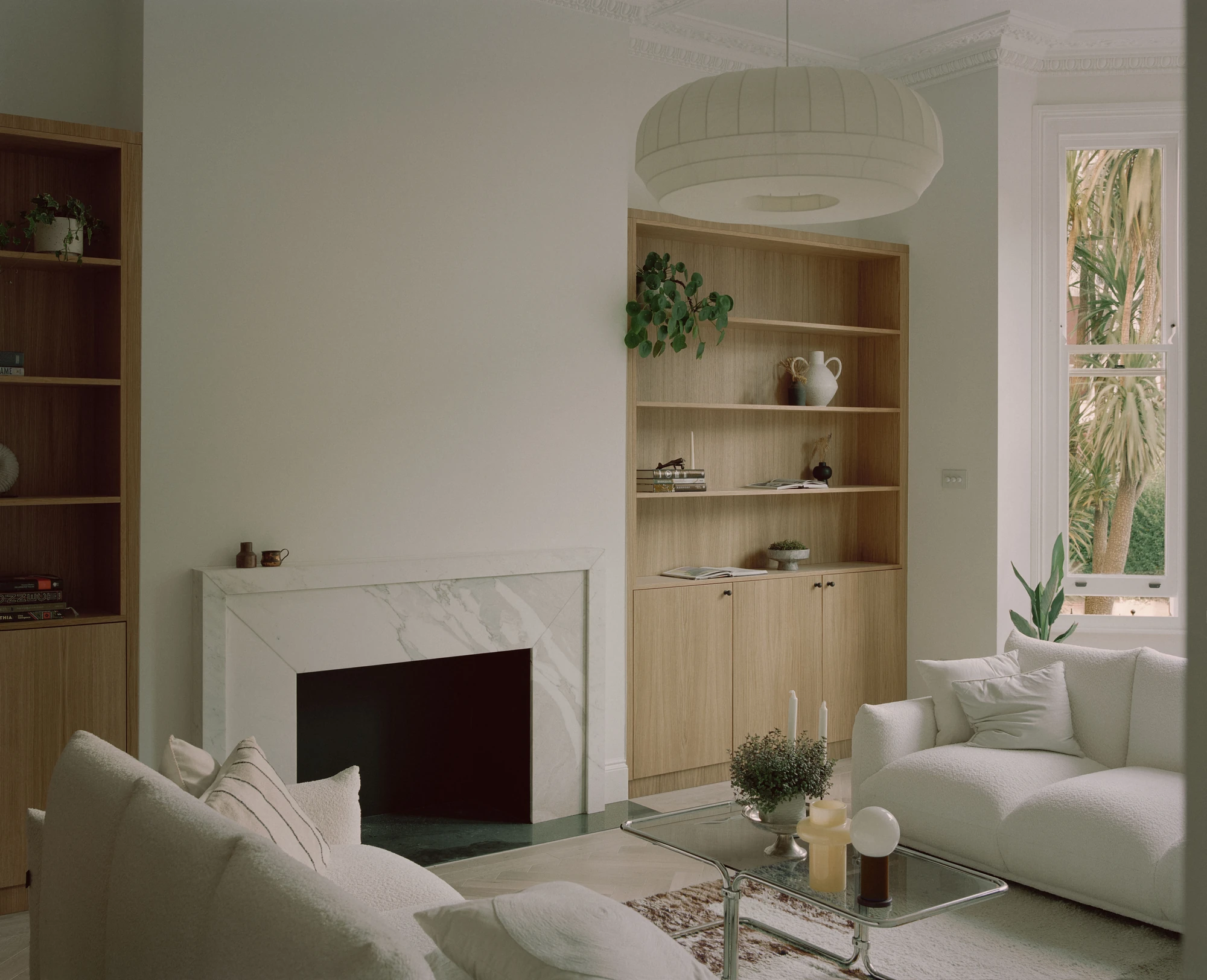Hampstead House by Twelve Forty One, photographed by Willem Pab — The fireplace with built-in oak shelving alongside, sofas drawn around a low table beneath a round pendant.