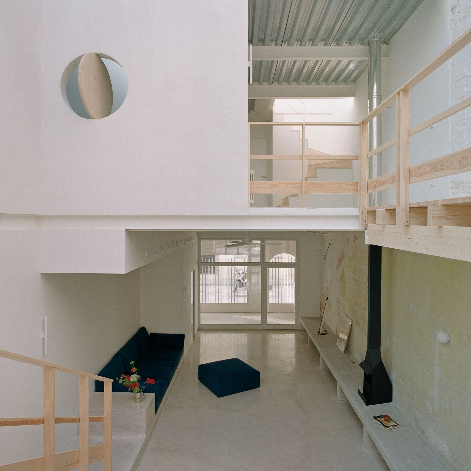 Villa V by Andrea Arriola Fiol and Adrián Mellado Muñoz, photographed by Del Rio Bani — Looking along the void from the upper floor, the ground floor below with its sofa and a round opening high in the wall